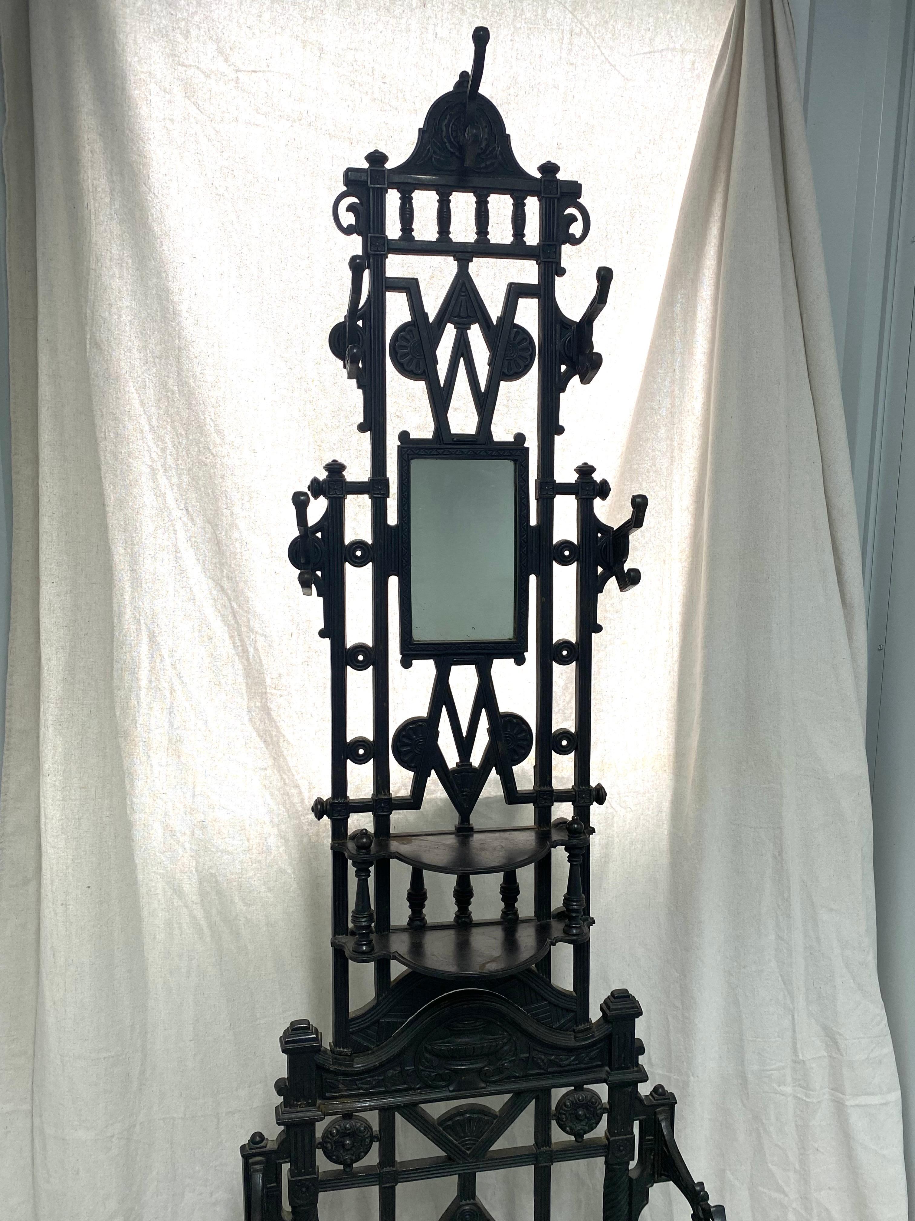 An English, Aesthetic Period cast iron hall tree by John and Thomas Cox of Birmingham. This design was registered on October 6, 1884. This Victorian hall tree features a mirror, shelf and ample room for umbrellas, canes, caps and coats. Old black