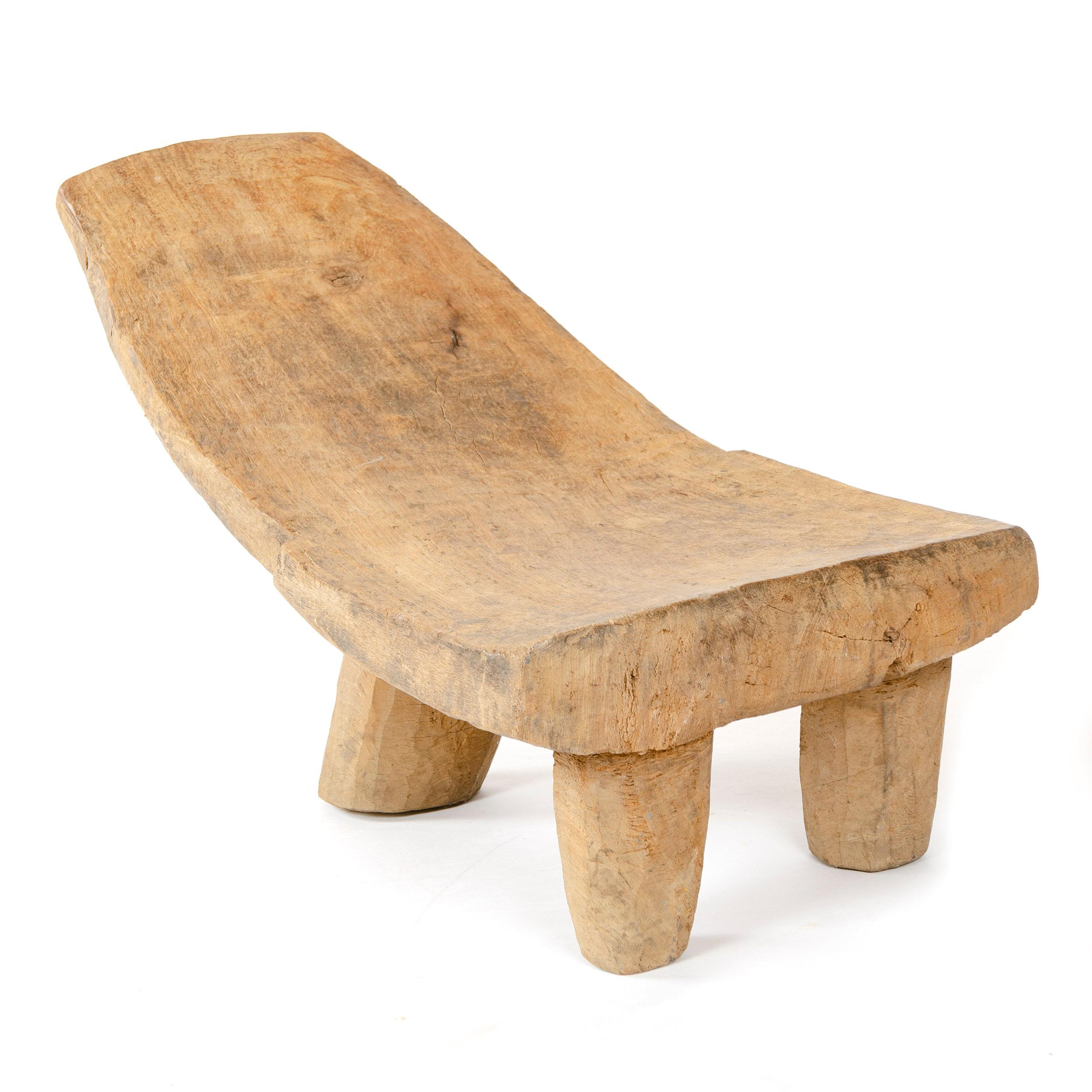 Une chaise africaine basse, sculptée dans une seule pièce de bois, ayant trois (3) pieds.