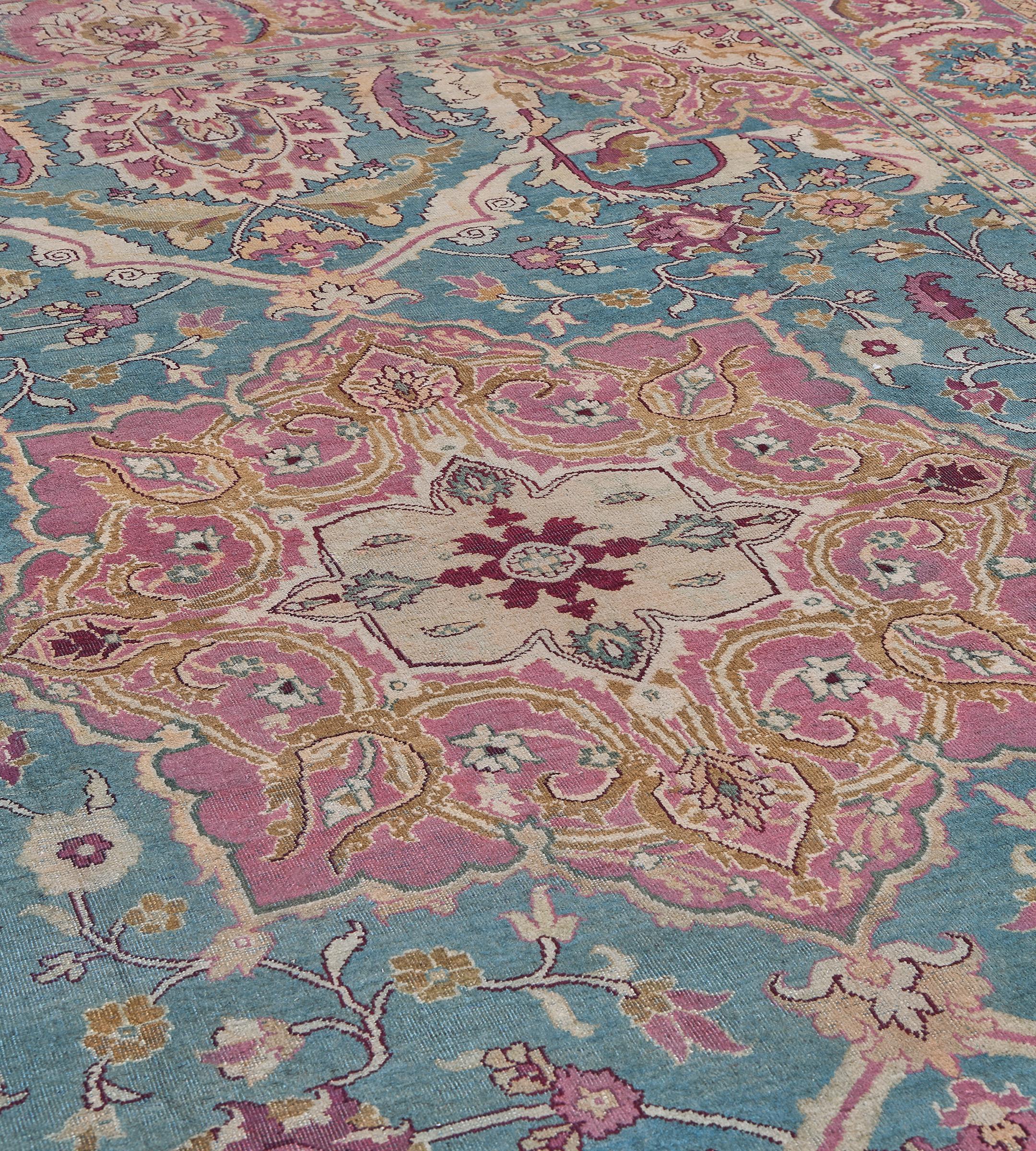 Questo tradizionale tappeto indiano Agra tessuto a mano presenta un elegante campo acquamarina contrapposto a tralci di palmette, che racchiude un medaglione arabescato color corallo sfumato, in un bordo complementare con palmette pendenti, tra