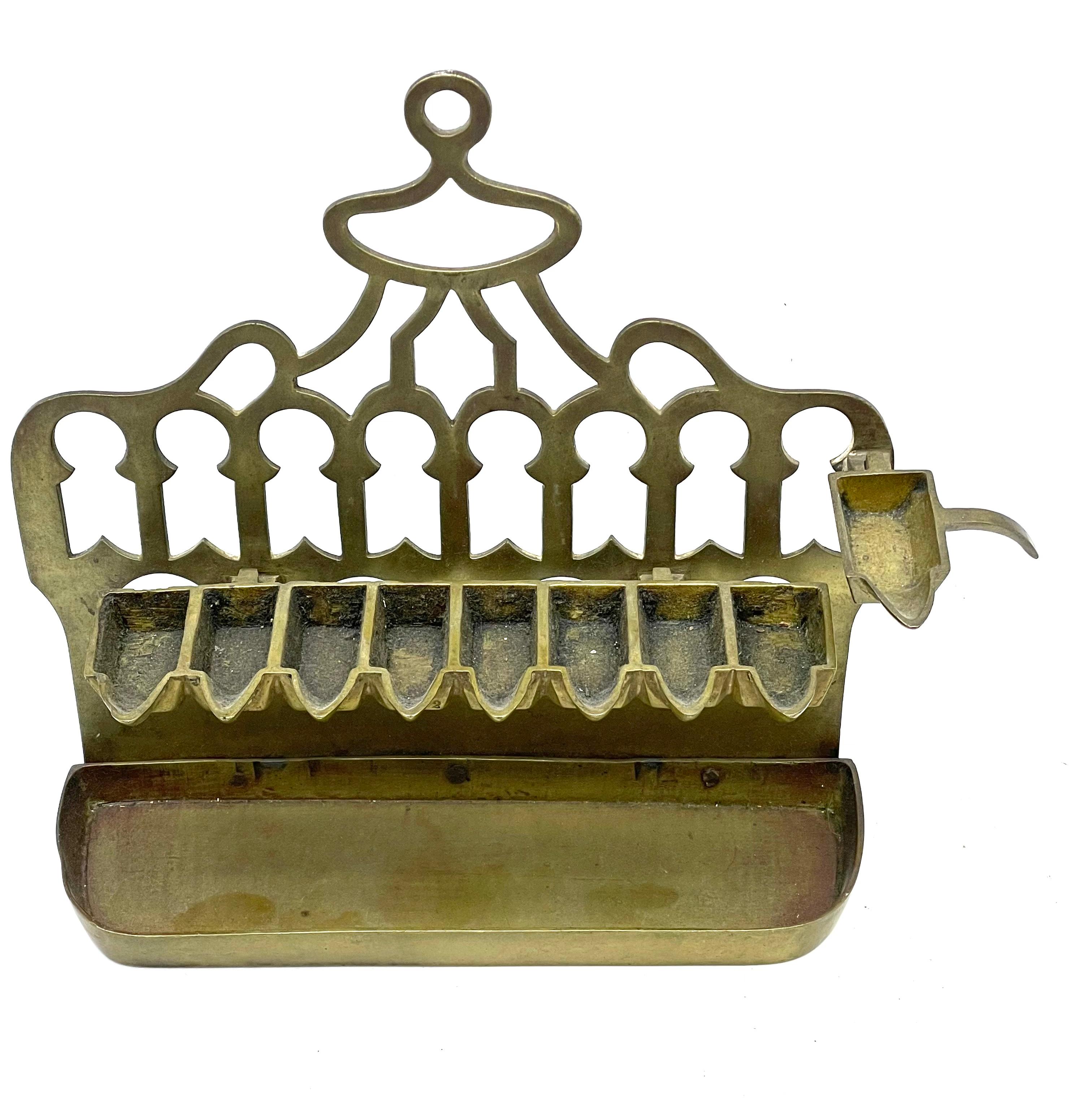 Eine Chanukka-Lampe aus Messingguss aus dem späten 19. Jahrhundert, hergestellt in Algerien. Die Lampe besteht aus drei zentralen Teilen: dem Korpus, einem Tablett für die Ölkerzen und einer Halterung für das Dienerlicht. Die Teile können zerlegt
