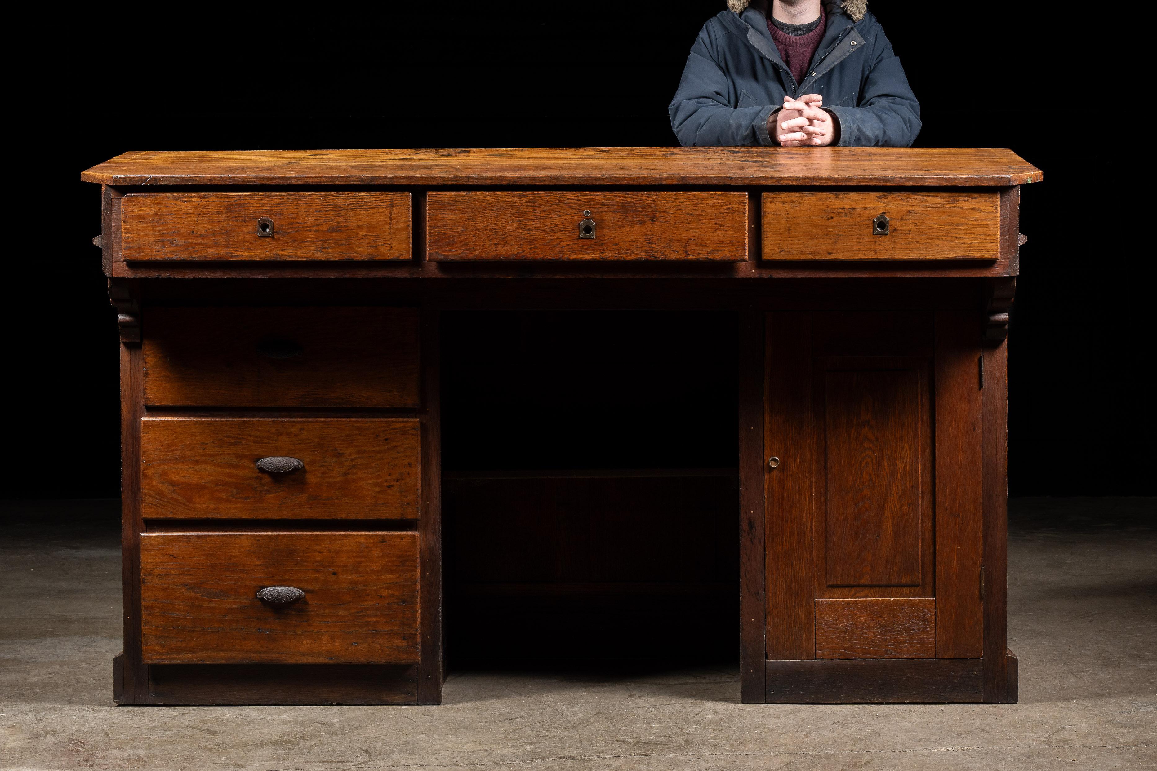 Antique wooden banking partner desk.

This piece is known as a partners desk and gets its name from the ability to host two bankers at once. The central cash drawer would have been utilized by both bank workers, while each person also had their own