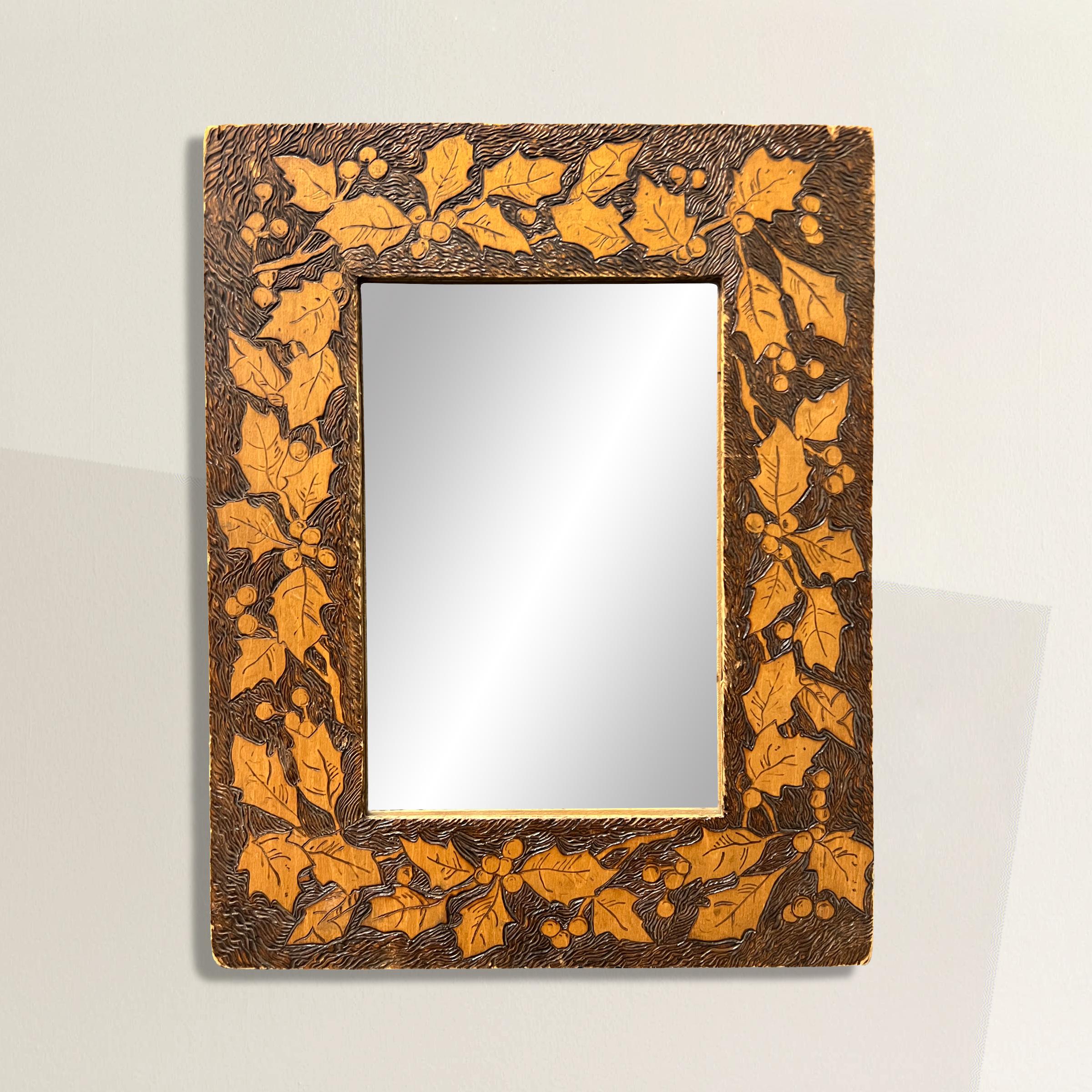 A sweet and sophisticated late 19th century American pyrography framed mirror with a hand-carved holly and berries pattern and a finely carved pattern behind the foliage. Pyrography is a 17th century technique that uses a heated poker to free-hand
