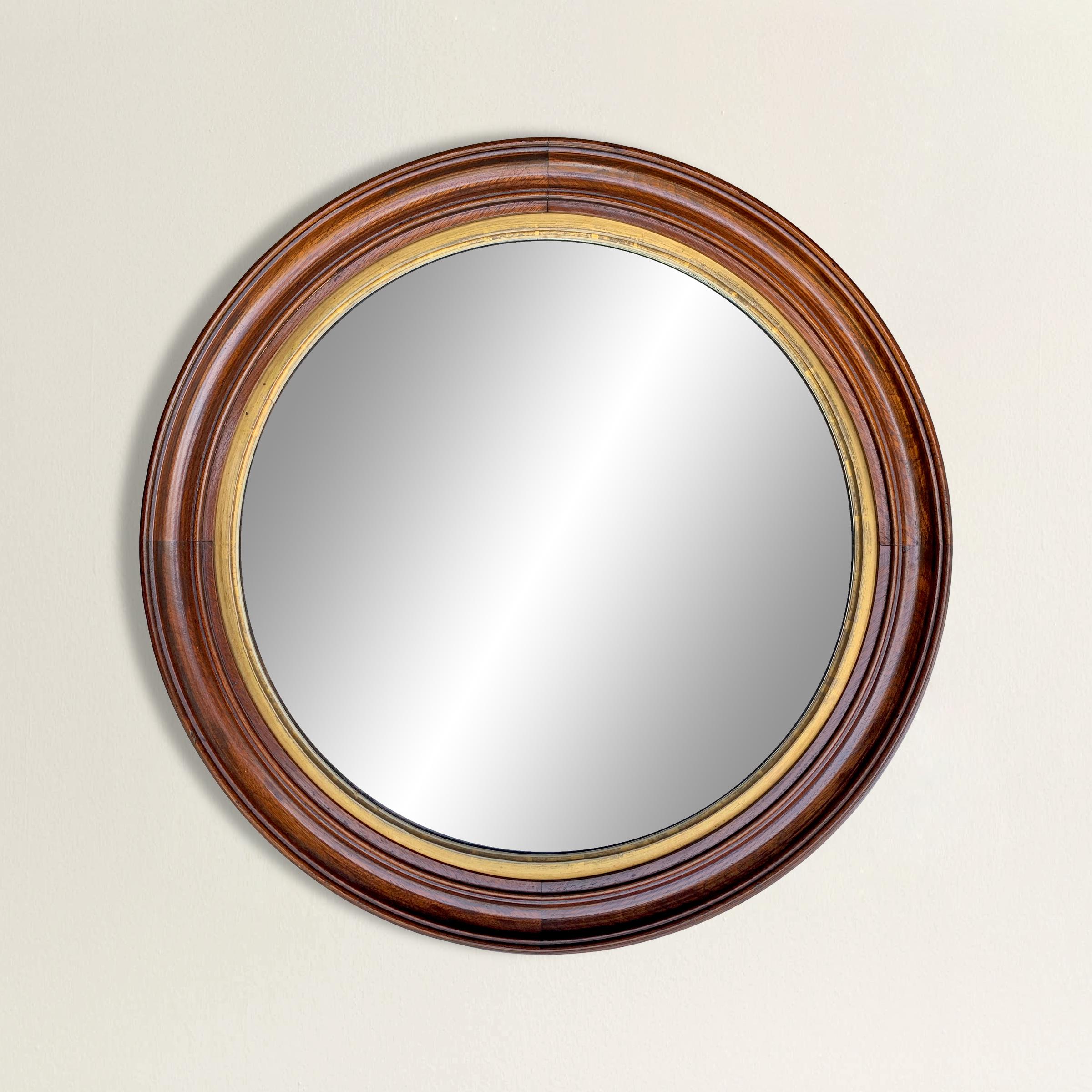 A striking late 19th century American mahogany framed round mirror with a gold leaf fillet and a wonderful deep cut sculptural frame profile.