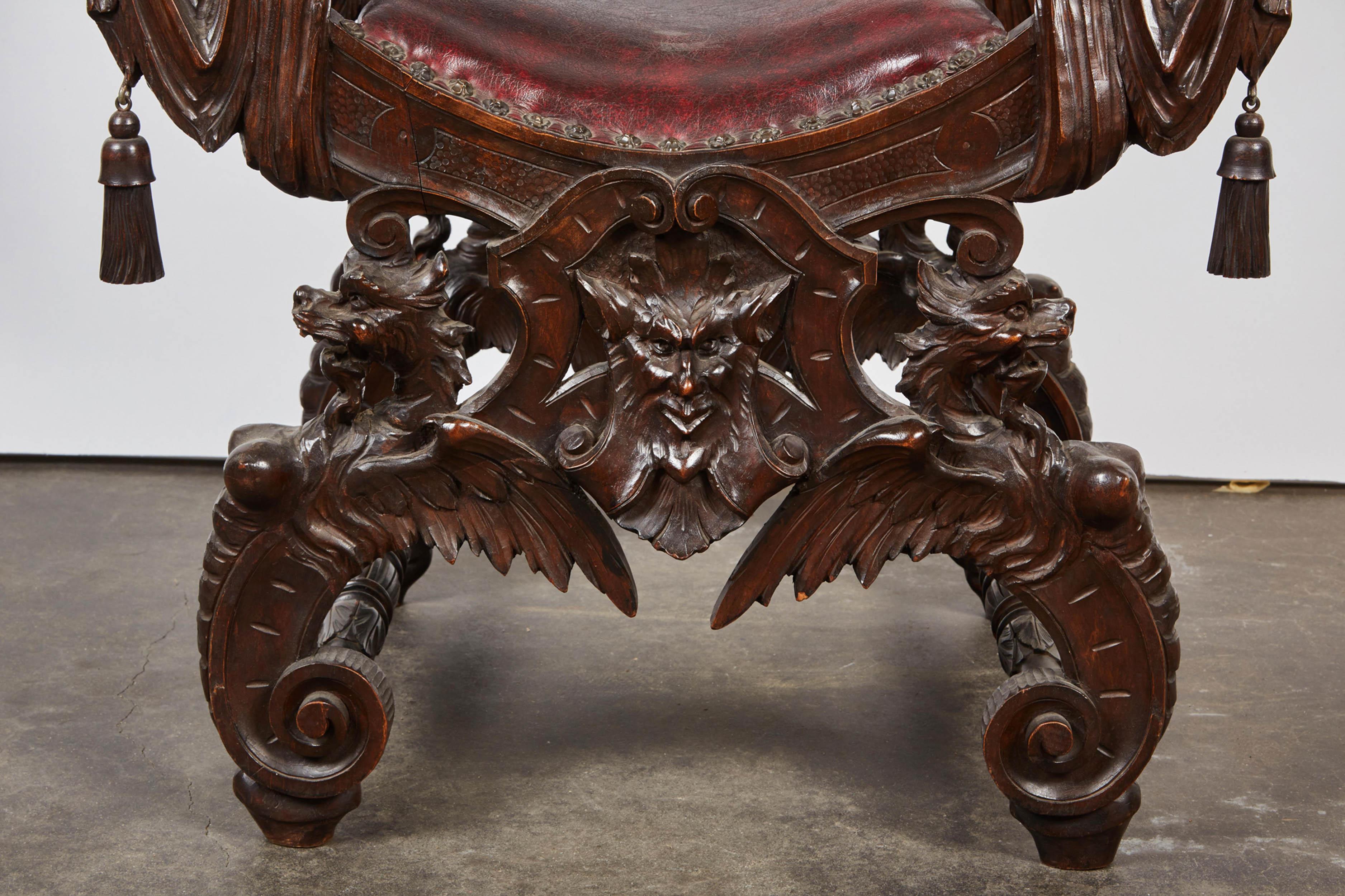 Savonarola chair from The Chicago School, possibly carved by Italian craftsman, chair having a crest with coat of arms above foliate back splat, high relief cherub and falcon carved arm rests, legs featuring a carved dragon, adorned with wooden