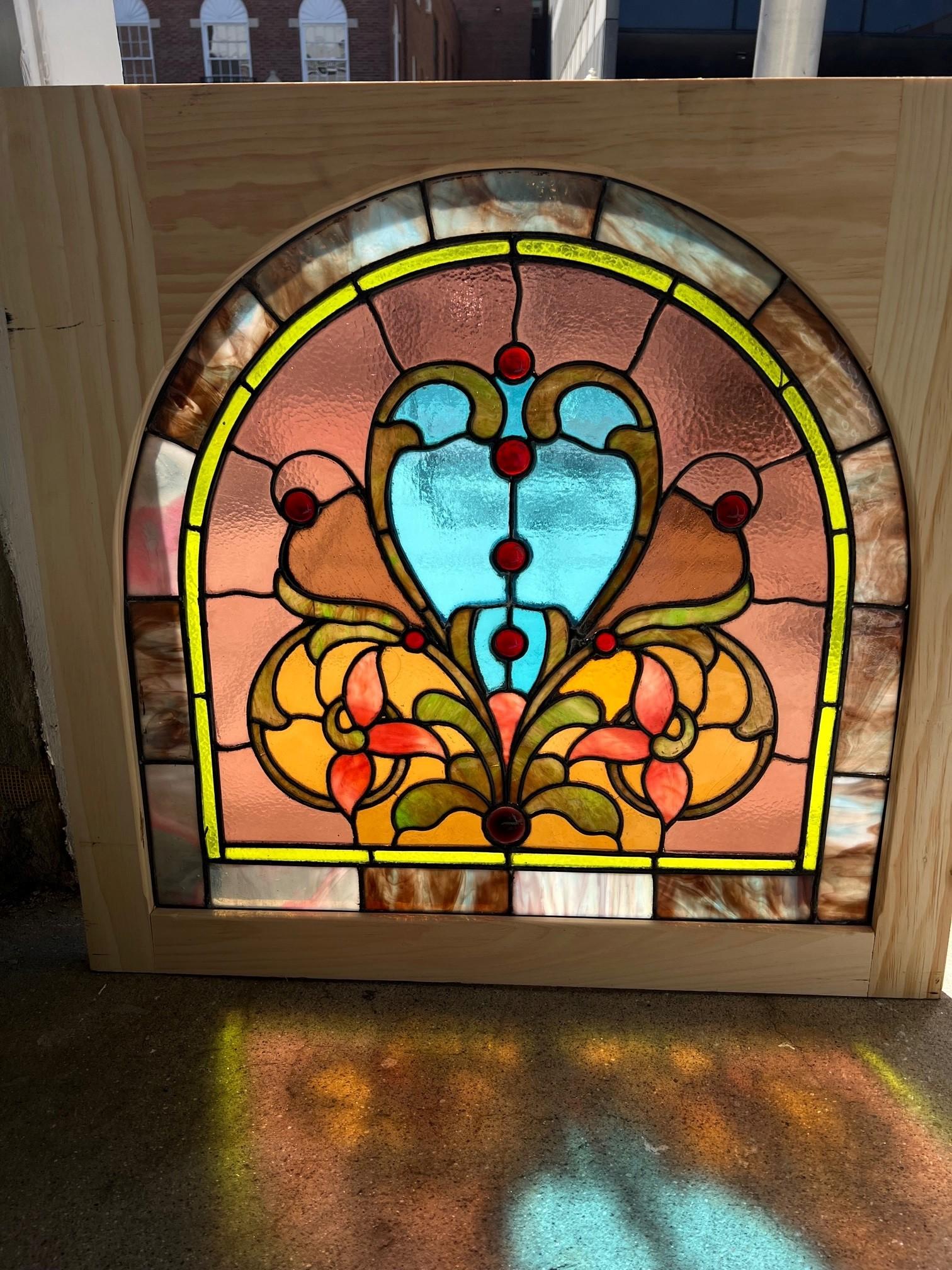 Beautiful 19th century antique stained glass window with an arch top in a new square wood frame. This window is full of color with a turquoise center that looks amazing in the sunlight. Salvaged from an estate outside Pittsburgh PA. this is a great