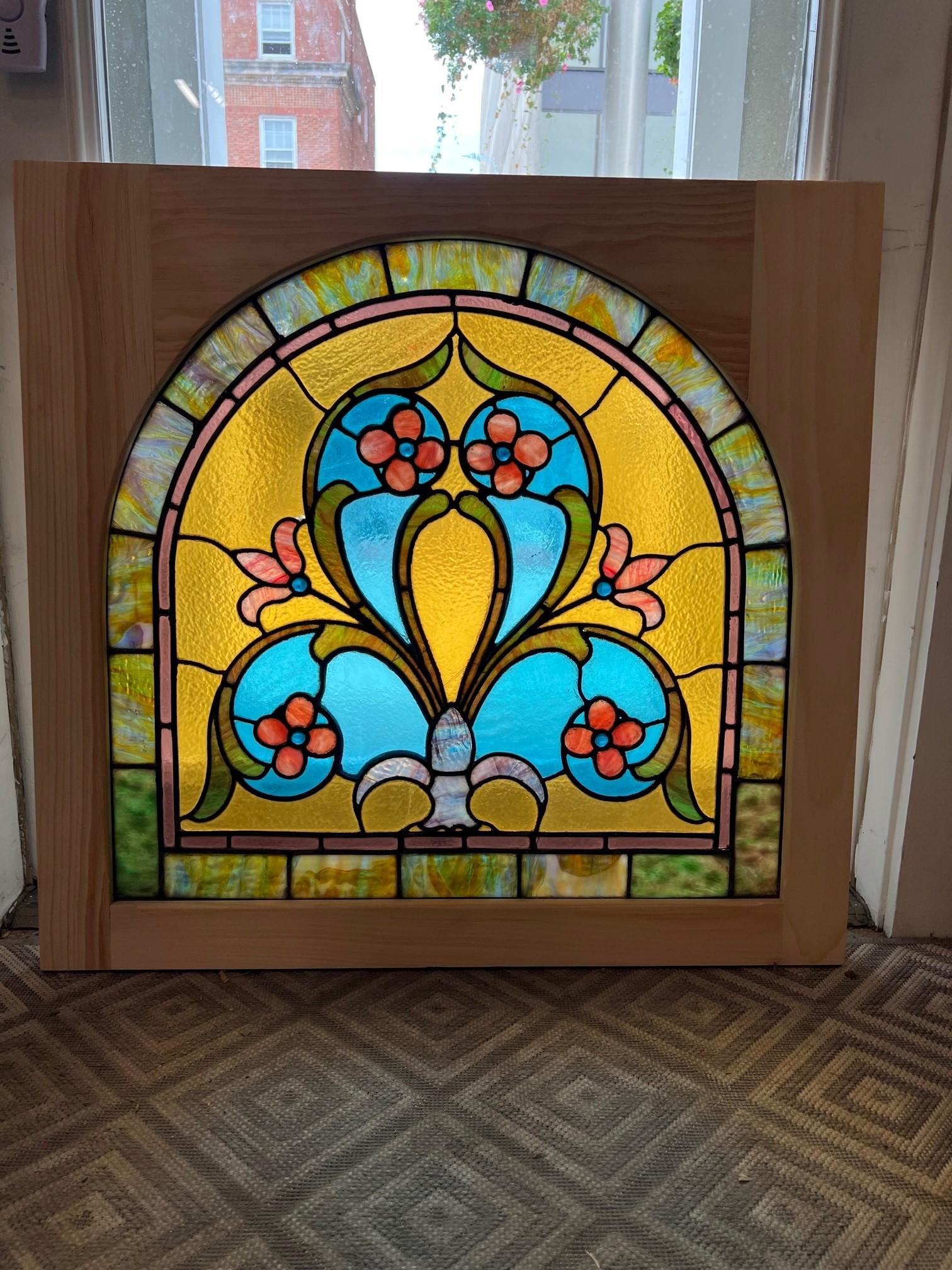 Beautiful antique arched top stained glass window with flowers and jewels. This antique stained glass window has been put into a new wood frame making it easy to hang and install. Salvaged from an estate outside Pittsburgh PA. with other windows I