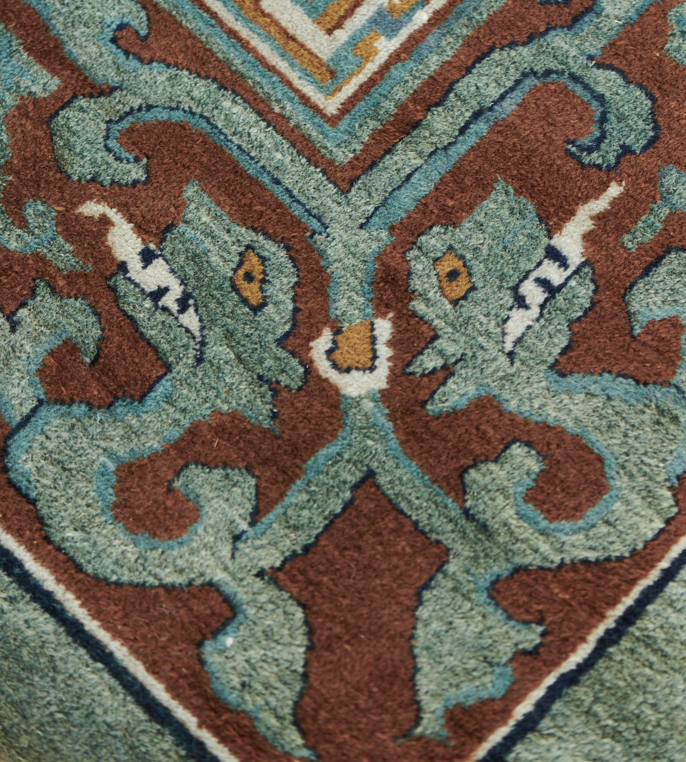 This antique Beijing rug from Northern China has an eau-de-nil field with an overall design of scattered ivory, golden-brown and indigo-blue flowerheads issuing angular leafy tendril vine stems surrounded by scattered butterflies,in a caramel-brown