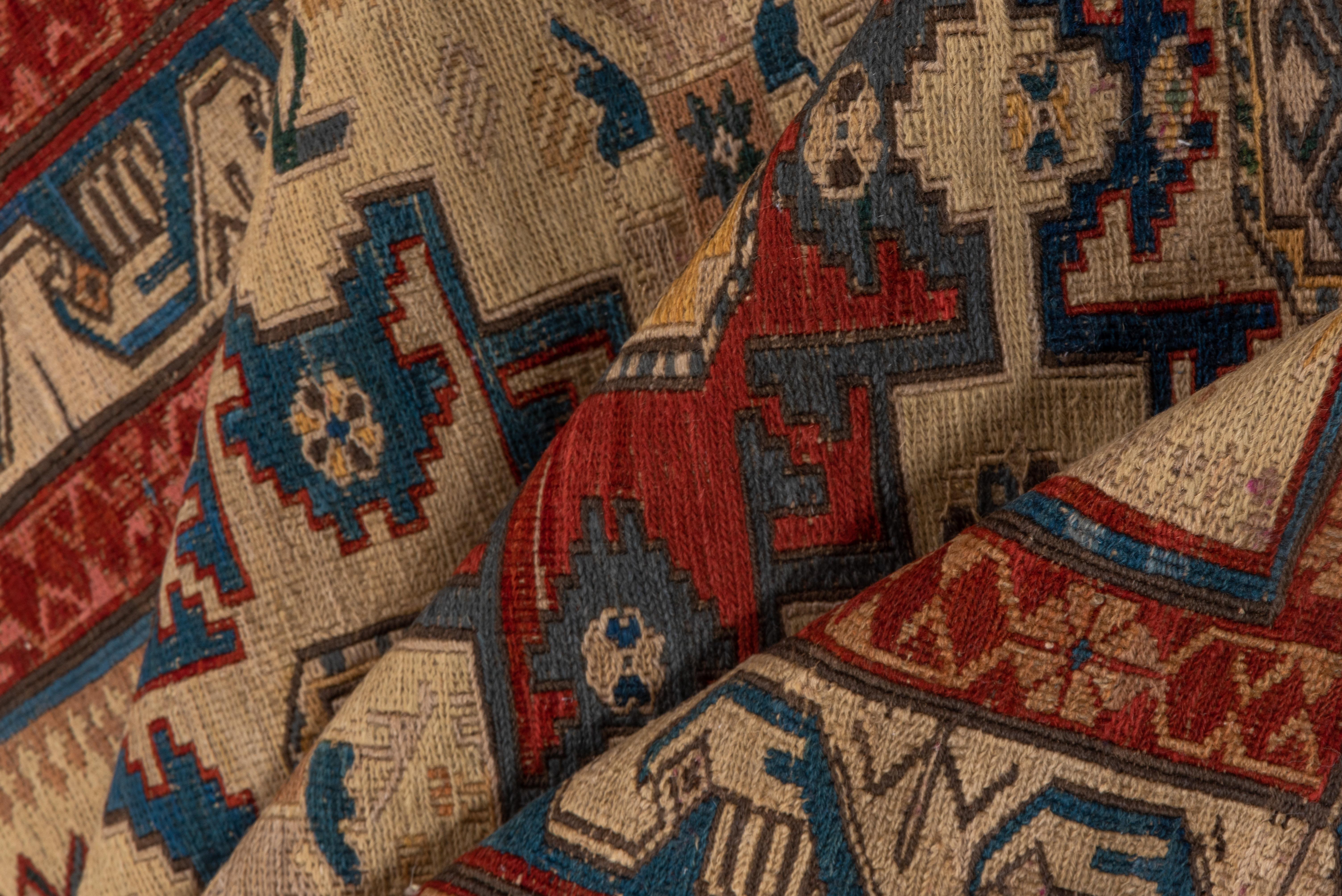 From the eastern Caucasus, this flatwoven Zeykhur kenare (runner) shows twelve slightly flattened Lesghi stars in red and green, and ivory and light blue on a light straw ground, within a characteristic light blue and white wave border and flanking