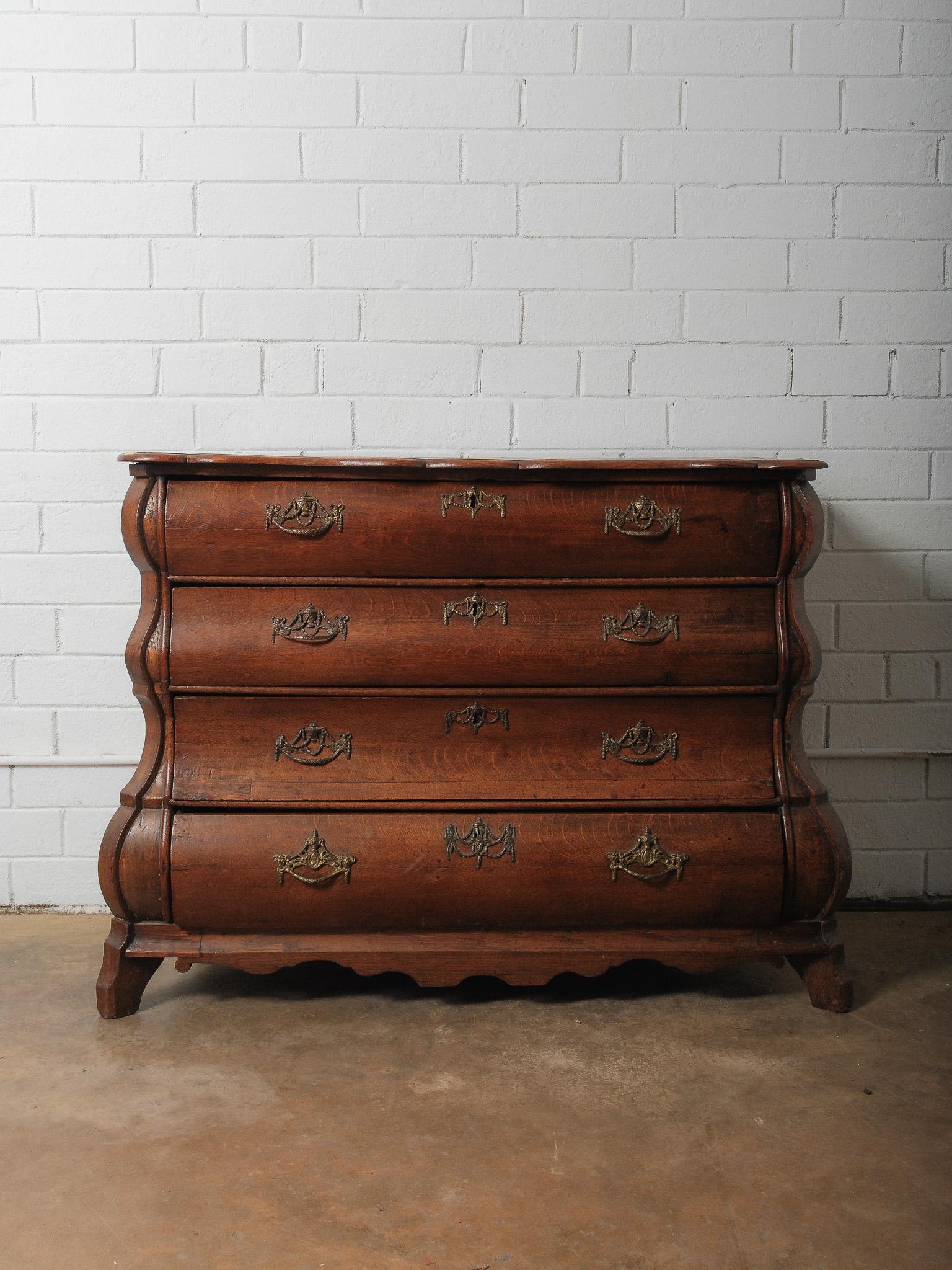 A striking late 19th-century Dutch bombe commode featuring a dramatically curved serpentine front and sides, crafted in richly grained solid oak with a warm, aged patina.

This elegant chest offers four deep drawers adorned with ornate cast brass