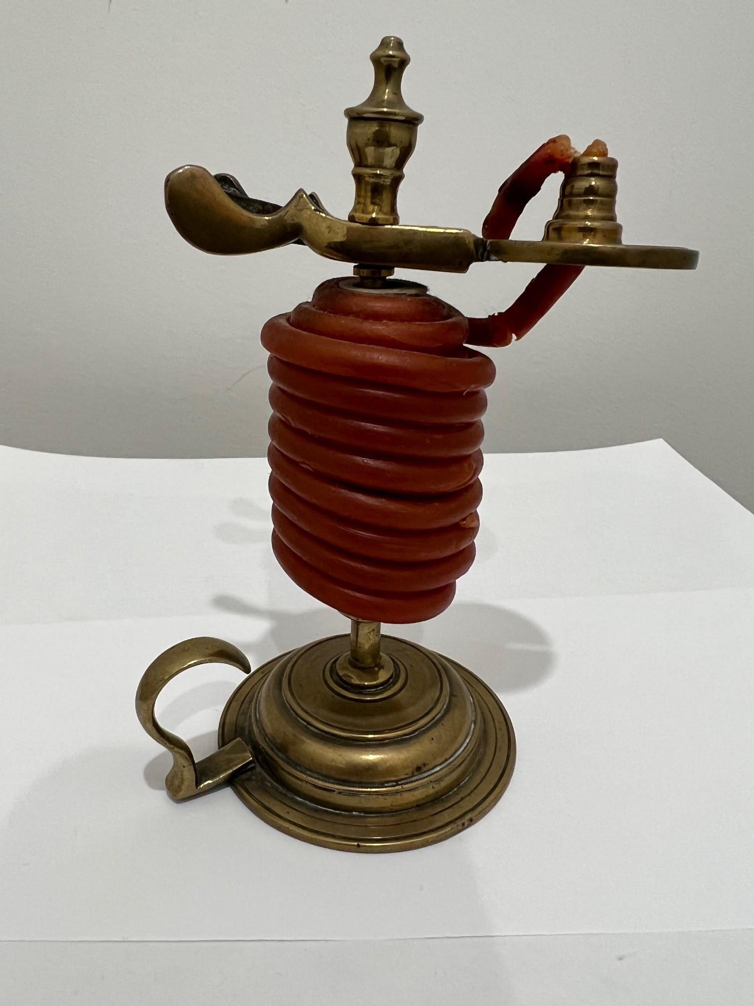 Cric de cire en laiton de la fin du 19e siècle, avec un levier de pouce et de la cire rouge sur un support avec un éteignoir. Un vérin à cire est un dispositif utilisé pour tenir un cône de cire à cacheter destiné à créer des scellements sur des