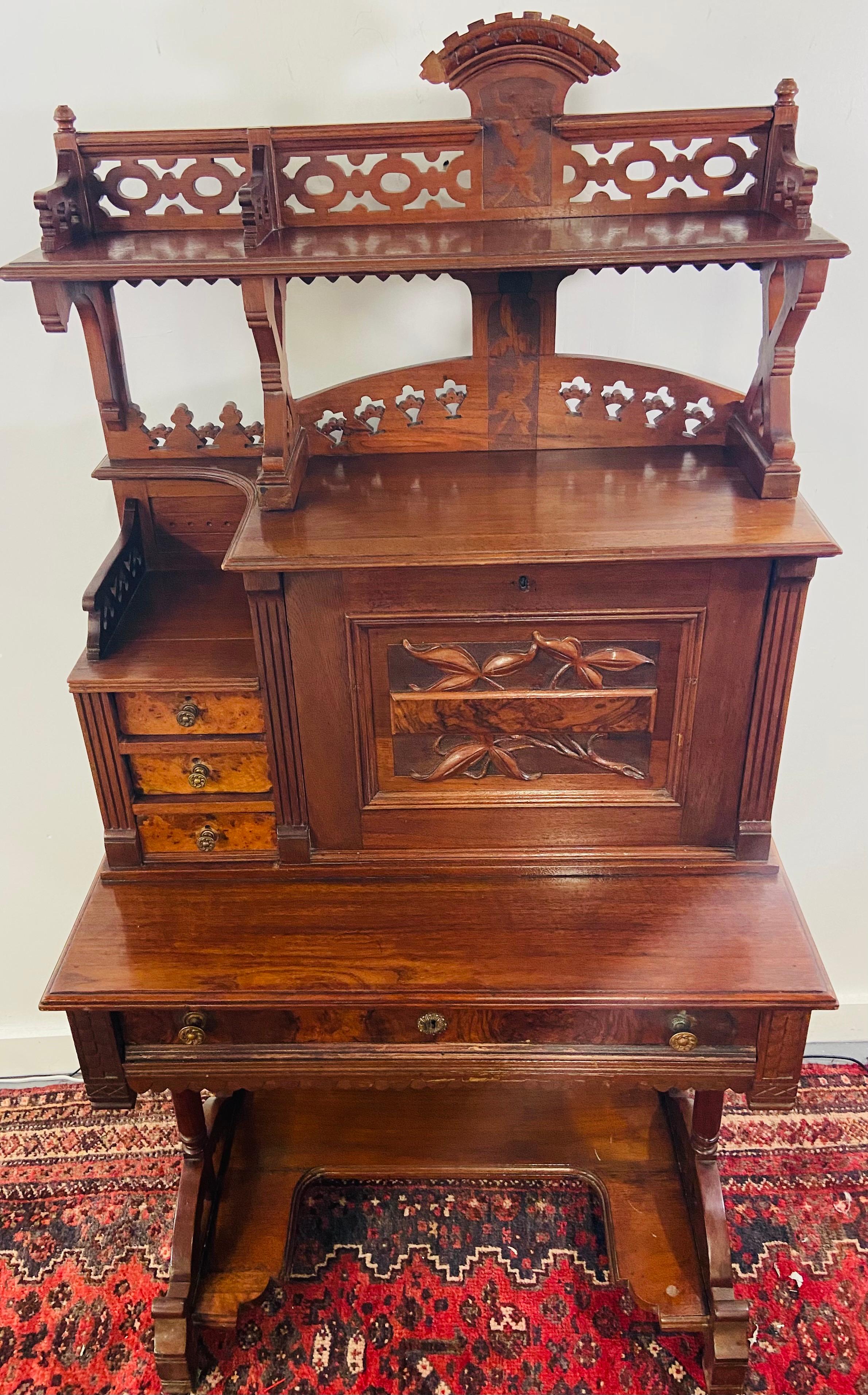 A gorgeous late 19th century English mahogany antique secretary desk. The desk features amazing carving design in both sides and front, a carved pediment top and bottom, three small side drawers and two shelves and one single drawer. The square
