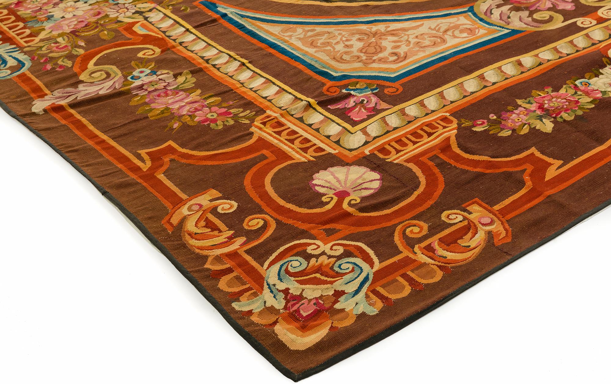 Made during the reign of Louis Philippe in Aubusson France, this elegant rug has a chocolate brown background with a delicate frame of florals and scrolls. The main field has a circular pattern highlighting the center of the rug decorated with a
