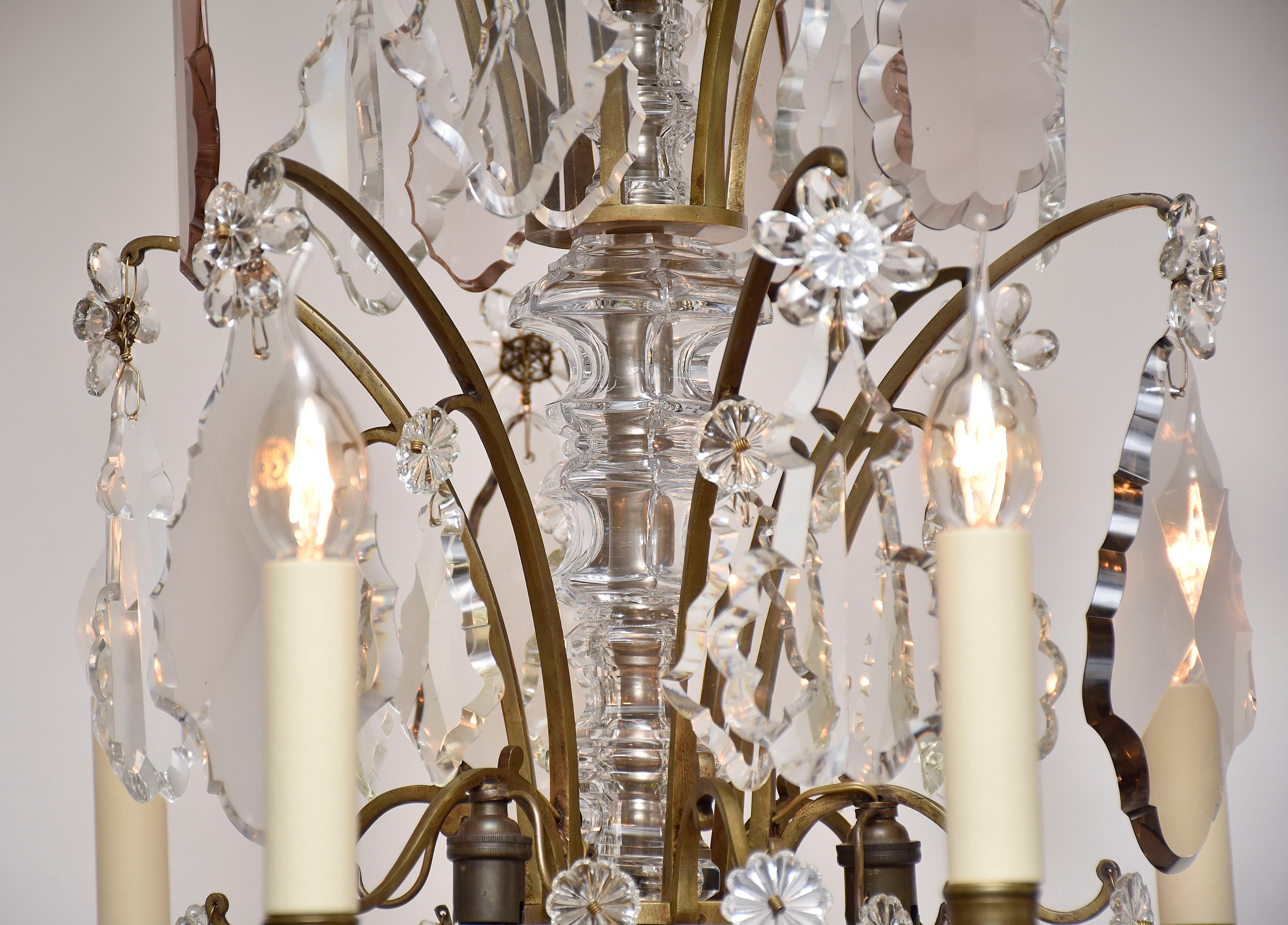 Un favoloso lampadario francese in bronzo 'lustre tige'.
Con 9 bracci a candela.
Al centro ci sono altre 3 piccole luci.
Lo stelo centrale è ricoperto da vasi decorativi sfaccettati. L'intero lampadario è appeso a numerosi cristalli trasparenti,