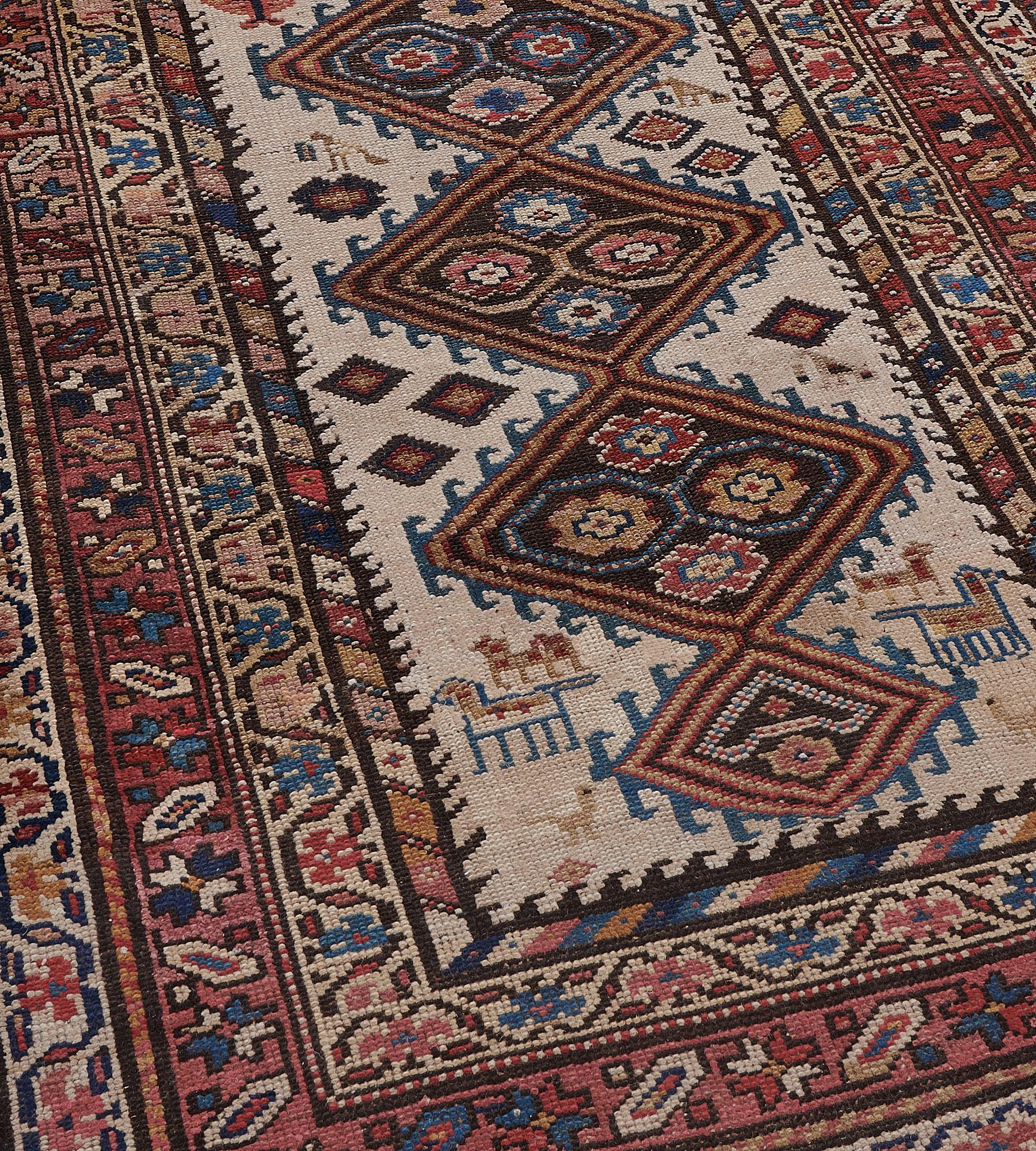 This antique Hamadan runner has an ivory field with a central column of linked and hooked lozenges each containing four polychrome angular flowerheads flanked by stylise boteh, surrounded by animal and floral motifs, inner polychrome diagonal hooked