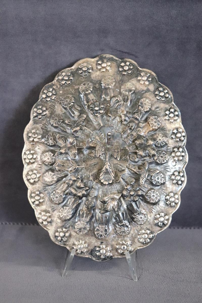 This antique hand mirror is truly rare. Characterized by a silverplate frame with rich floral relief decoration with flowers and birds. The mirror is antique mercury and has imperfections. A true collector's item.