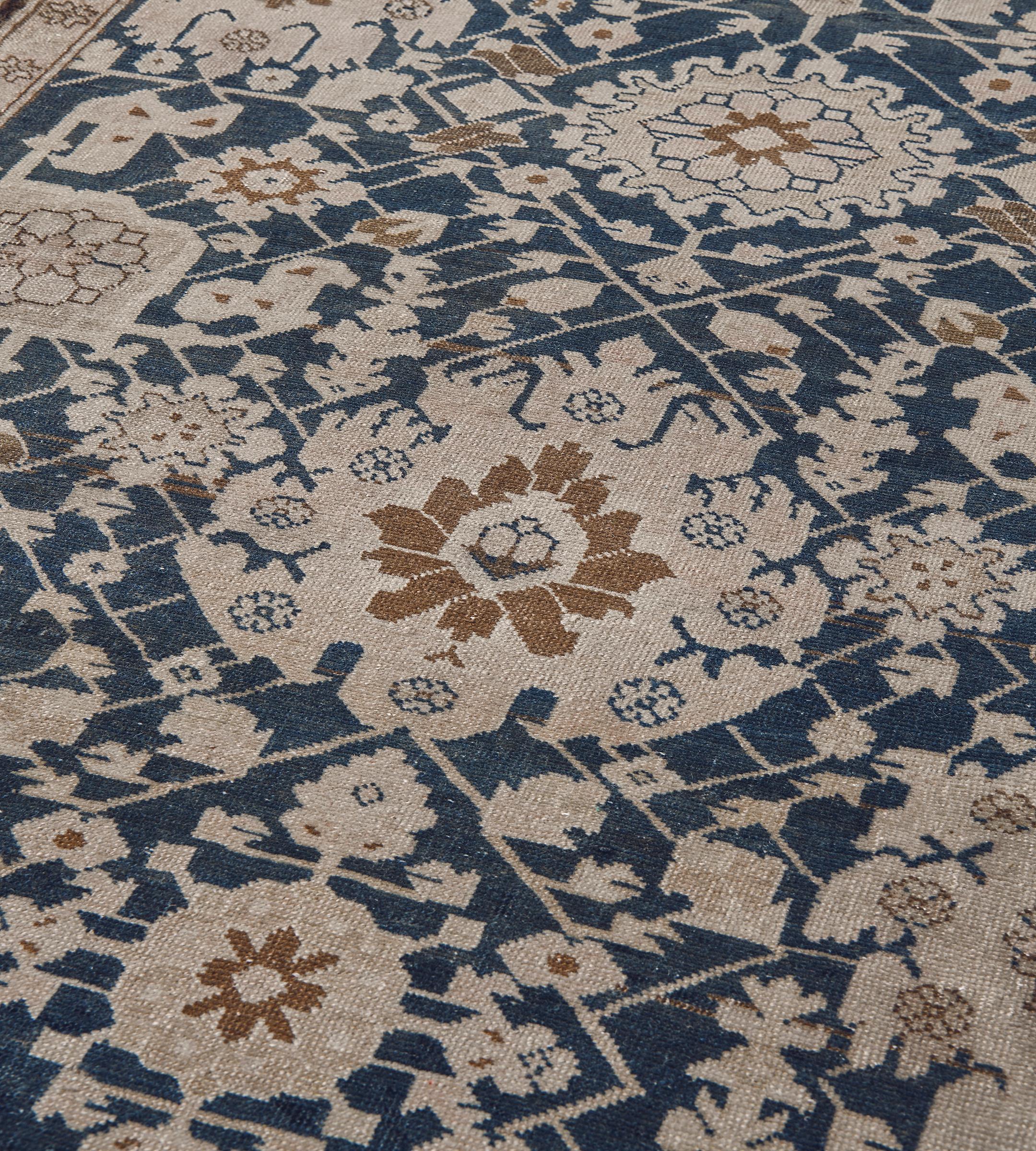 Cet antique chemin de table du Karabagh présente un champ bleu indigo avec un motif général composé d'une colonne centrale de palmettes brun chamois reliées par des têtes de fleurs angulaires et des feuilles de vigne dentelées, reliées de chaque