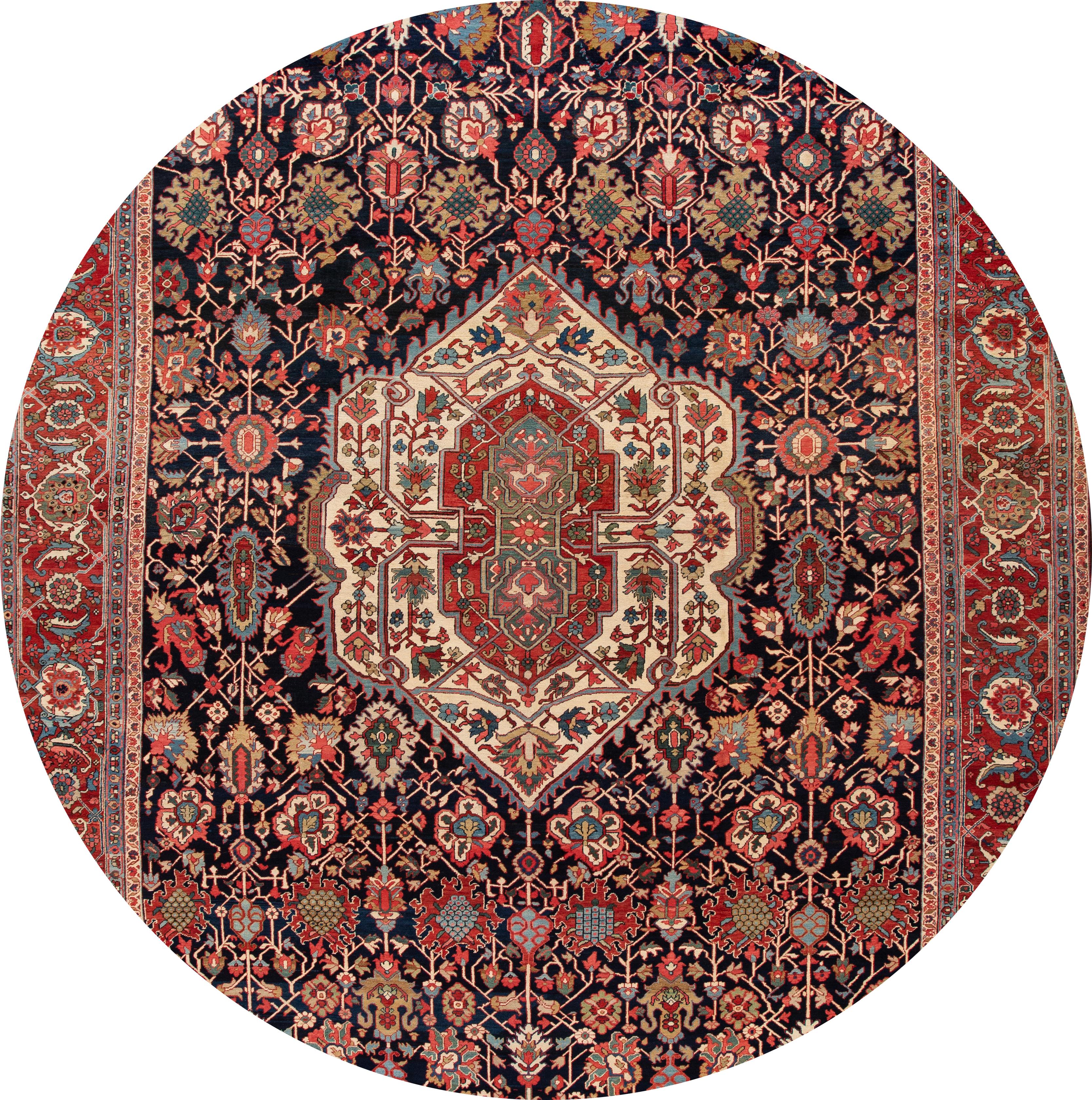 Beautiful antique oversize Persian Heriz rug, hand knotted wool with a navy blue, red field, and multi-color accents in a multi-medallion design.
This hand knotted wool rug measures 14' 10