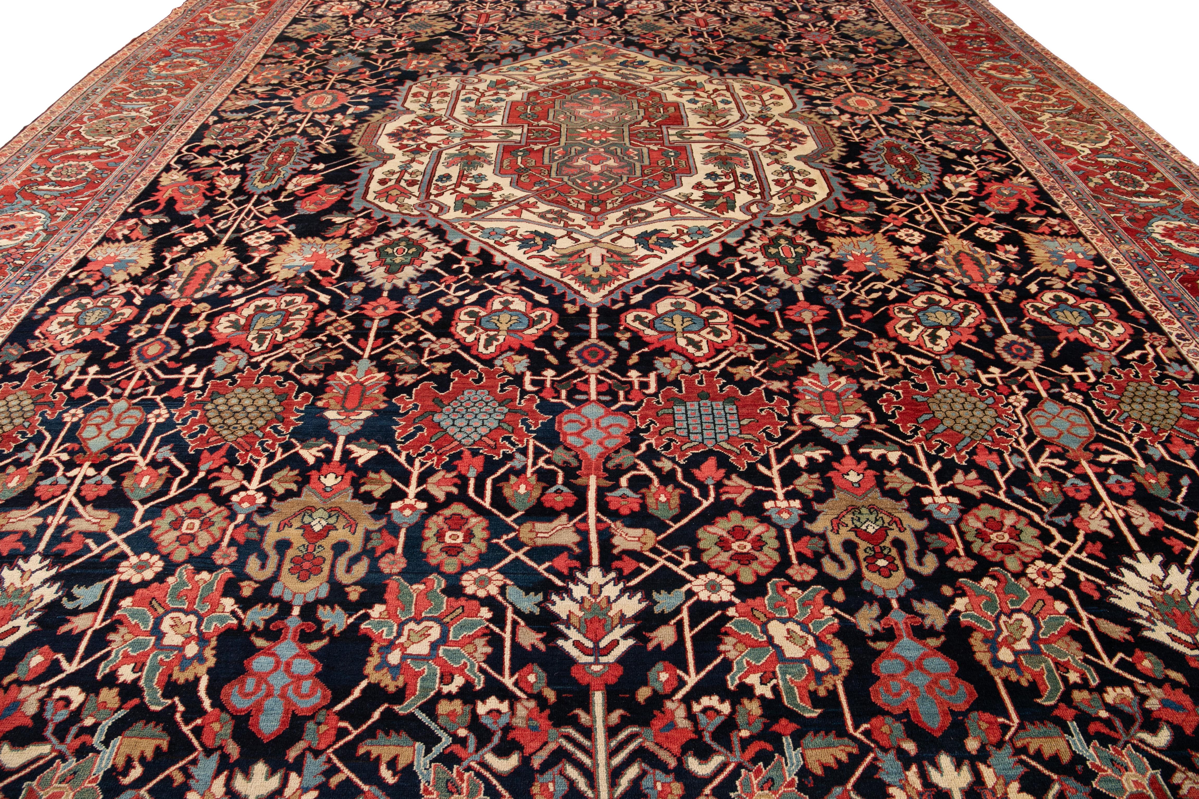 Schöner antiker übergroßer persischer Heriz-Teppich, handgeknüpft aus Wolle mit einem marineblauen, roten Feld und mehrfarbigen Akzenten in einem Multi-Medaillon-Design.
Dieser handgeknüpfte Wollteppich misst 14' 10
