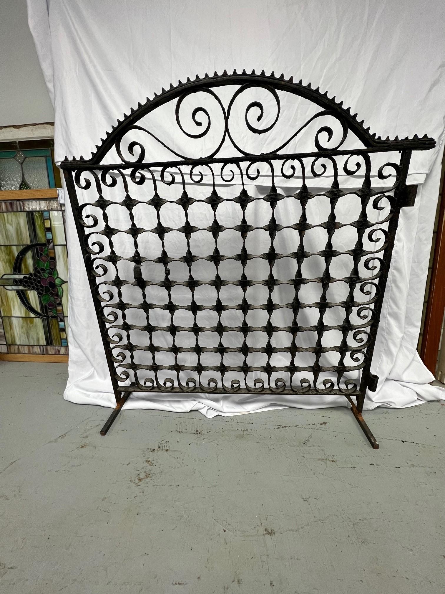Late 19th century decorative iron arched gate salvaged from a NYC. Brownstone. This is a nice original iron gate in very good condition and a great size with a nice arch top. The gate has been modified with two iron stands or feet which allow the