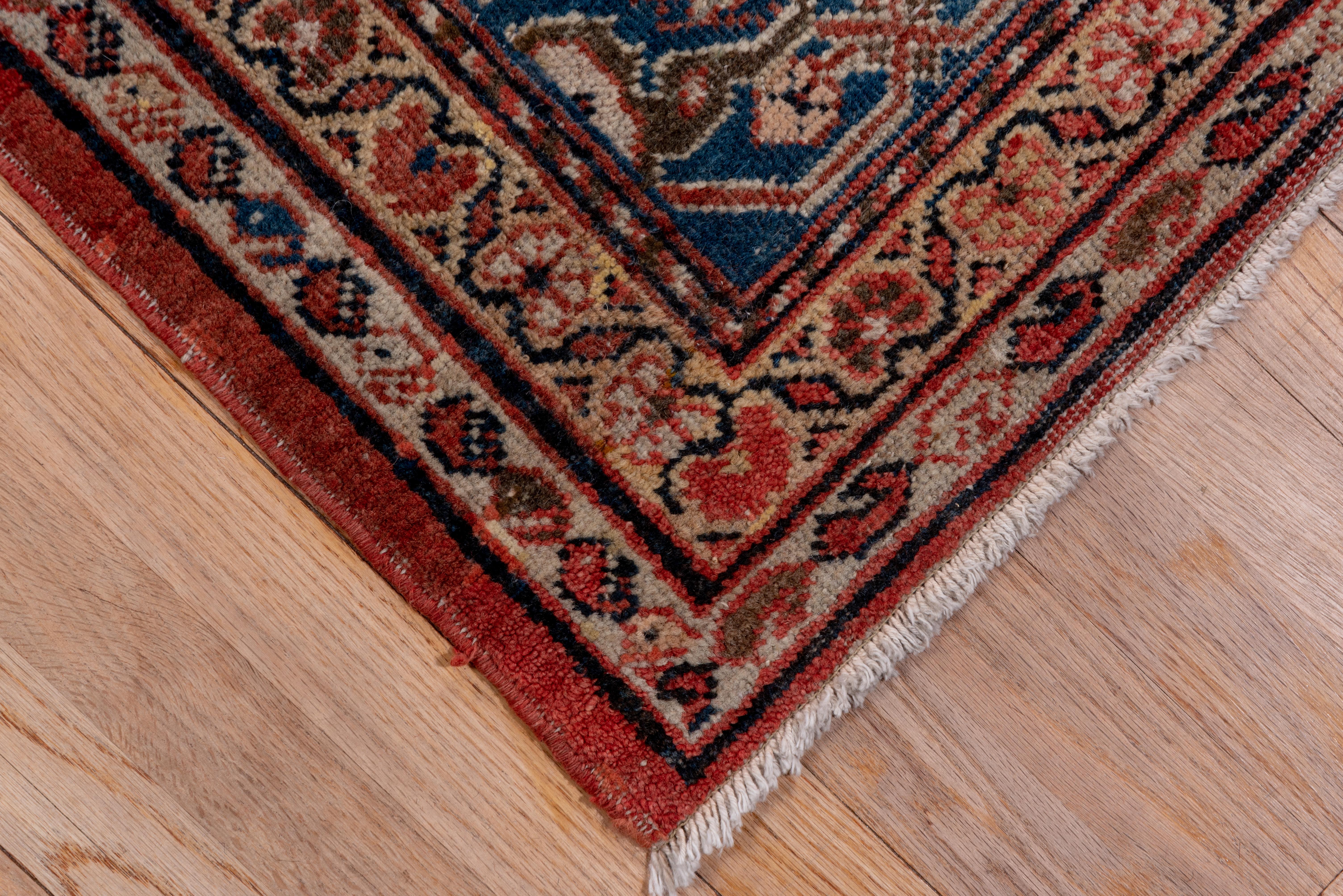 This good condition west Persian village carpet shows a large-scale all-over pattern of straw and ivory vertical lozenges and horizontal cartouches, all with complex rosette and leaf patterns. The ground is a soft, lightly abrashed madder red. The