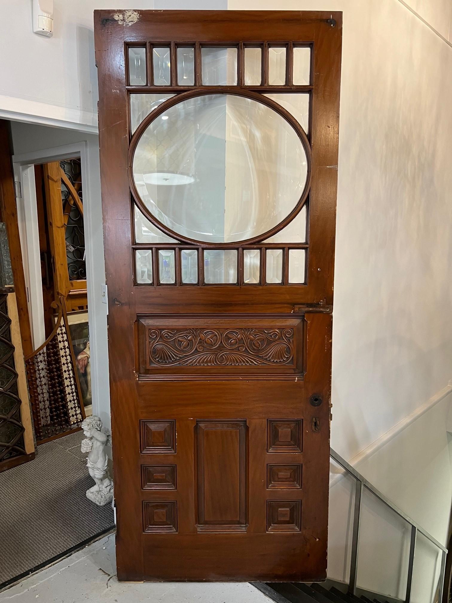 Beautiful mahogany oversized entrance door with beveled glass and a carved wood panel. The oval window with its wide cut beveled glass and the smaller panels make it look amazing in the sunlight. Its also a great size for a grand entrance or used as