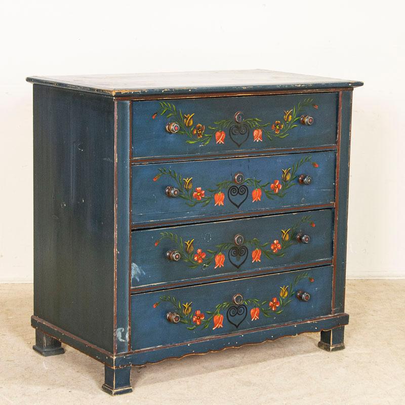 The vibrant colors are all original on this blue painted antique chest of 3 drawers. The floral embellishments of tulips and hearts were traditional elements of Swedish country painting. The whimsical flowers and bright colors create a cheerful feel