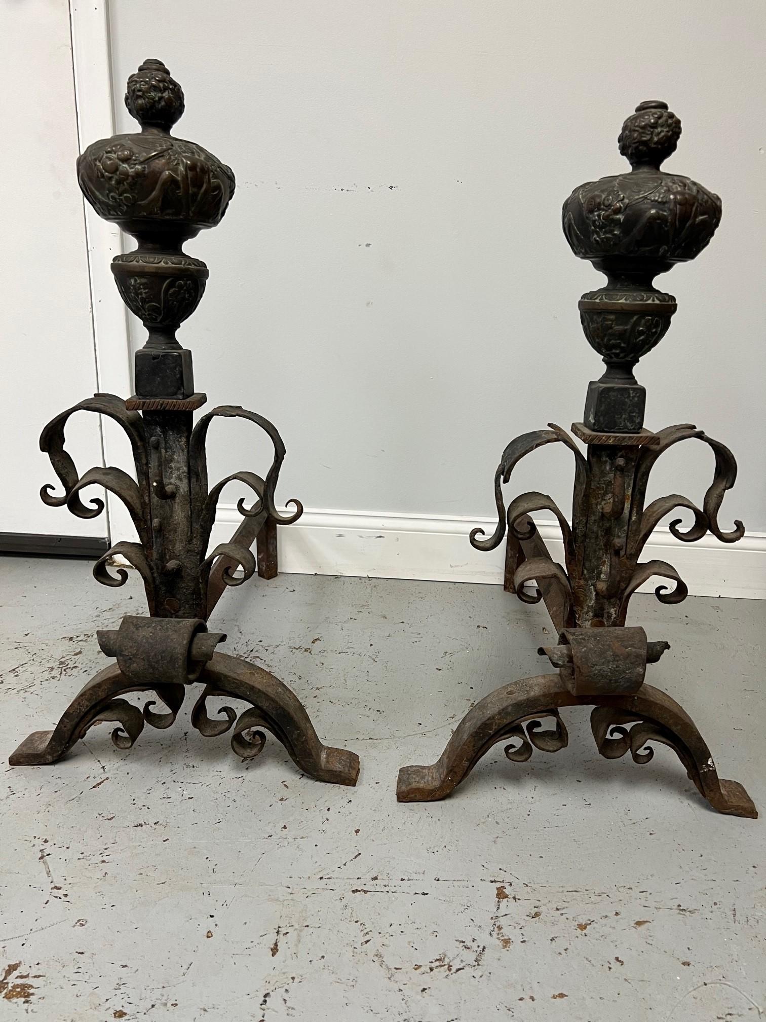 Antique pair of iron and bronze andirons from the late 19th Century. This is a nice pair of andirons a combination of iron and bronze. The bronze ball have winged figures with a great patina and a nice size. They are in good original condition and