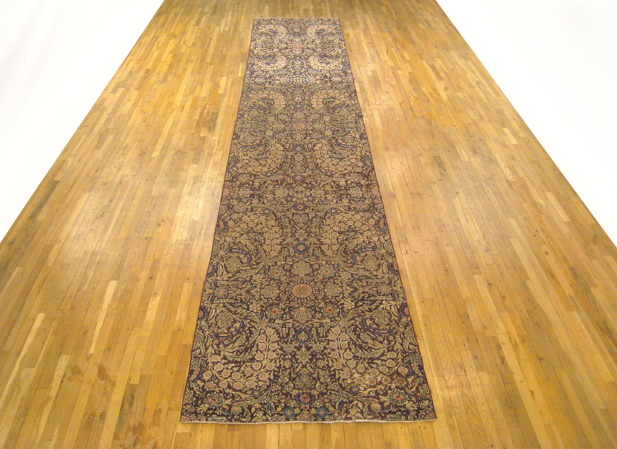 An antique Persian Lavar Oriental rug in runner size, circa 1870, size 19'0 x 3'9. This lovely hand knotted carpet features a dazzling floral design in the ivory central field, alternating between small scale and large scale floral elements. The