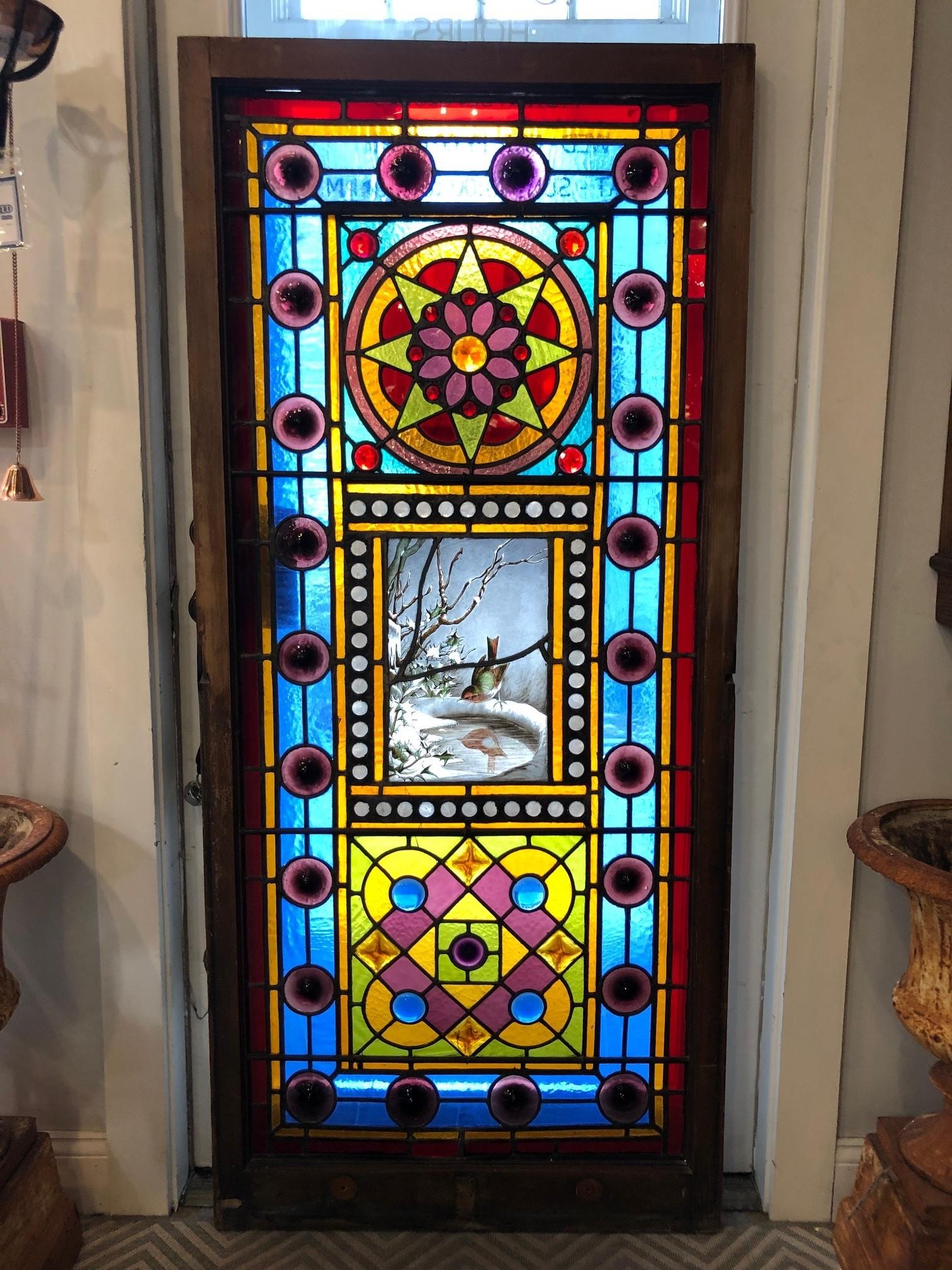 Late 19th century Victorian Stained glass window with a hand painted center panel of a small bird seeing its reflection in a frozen birdbath, the detail is simply amazing. The brilliant colors and 65 multi faceted jewels with 22 rondels around the