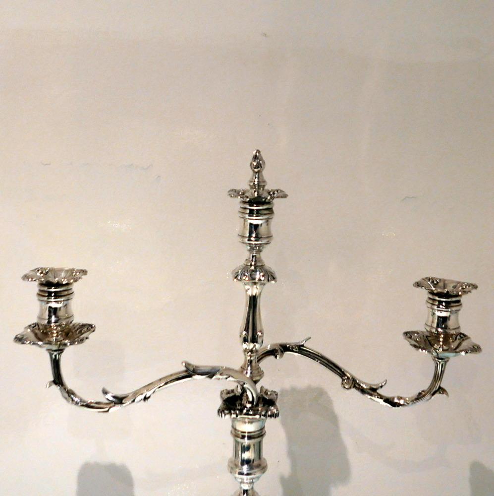 A stunning pair of three light Victorian plate candelabra made by the highly renowned manufacturer Elkington & Co. The bases are shaped square and have elegant shell designs at the angles. The branches have a naturalistic theme and interchange into