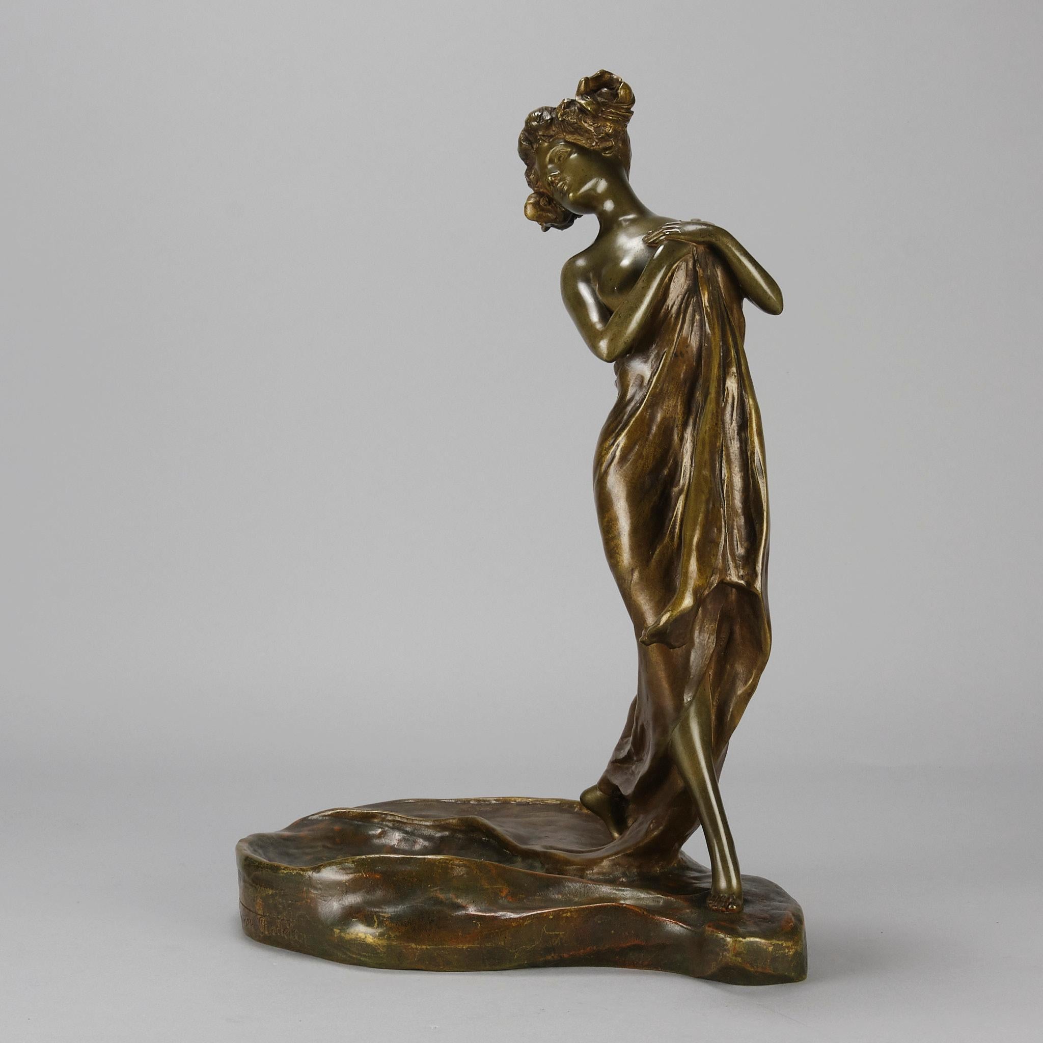 Eine reizvolle Jugendstil-Bronzefigur einer jungen, spärlich bekleideten Schönheit, die nur einen Schal über ihren Körper drapiert hat und eine auffällige Pose einnimmt. Die Oberfläche der Bronze mit reicher goldbrauner Patina und feinen