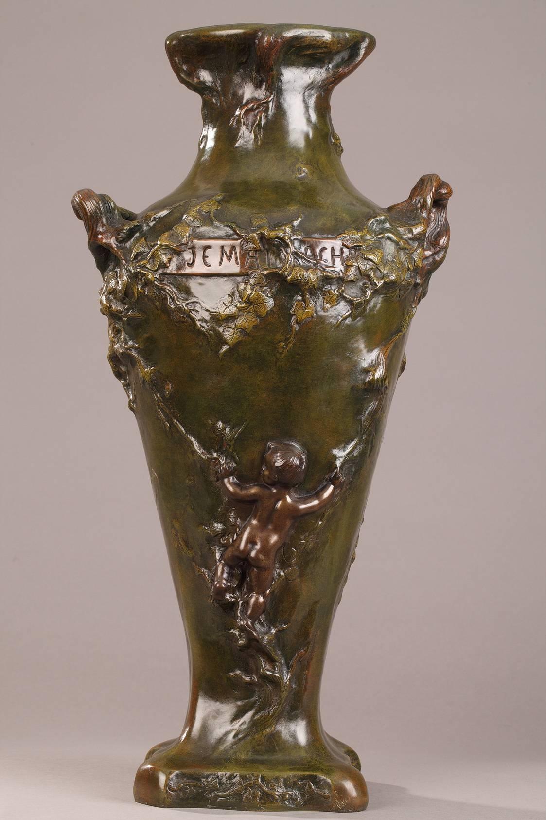 Large, bronze amphora vase with green, brown, and yellow patination. The front of the paunch is decorated with a naiad, lying on waves and surrounded by aquatic plants. On the other side of the vase, a cupid, seen from behind, is climbing the