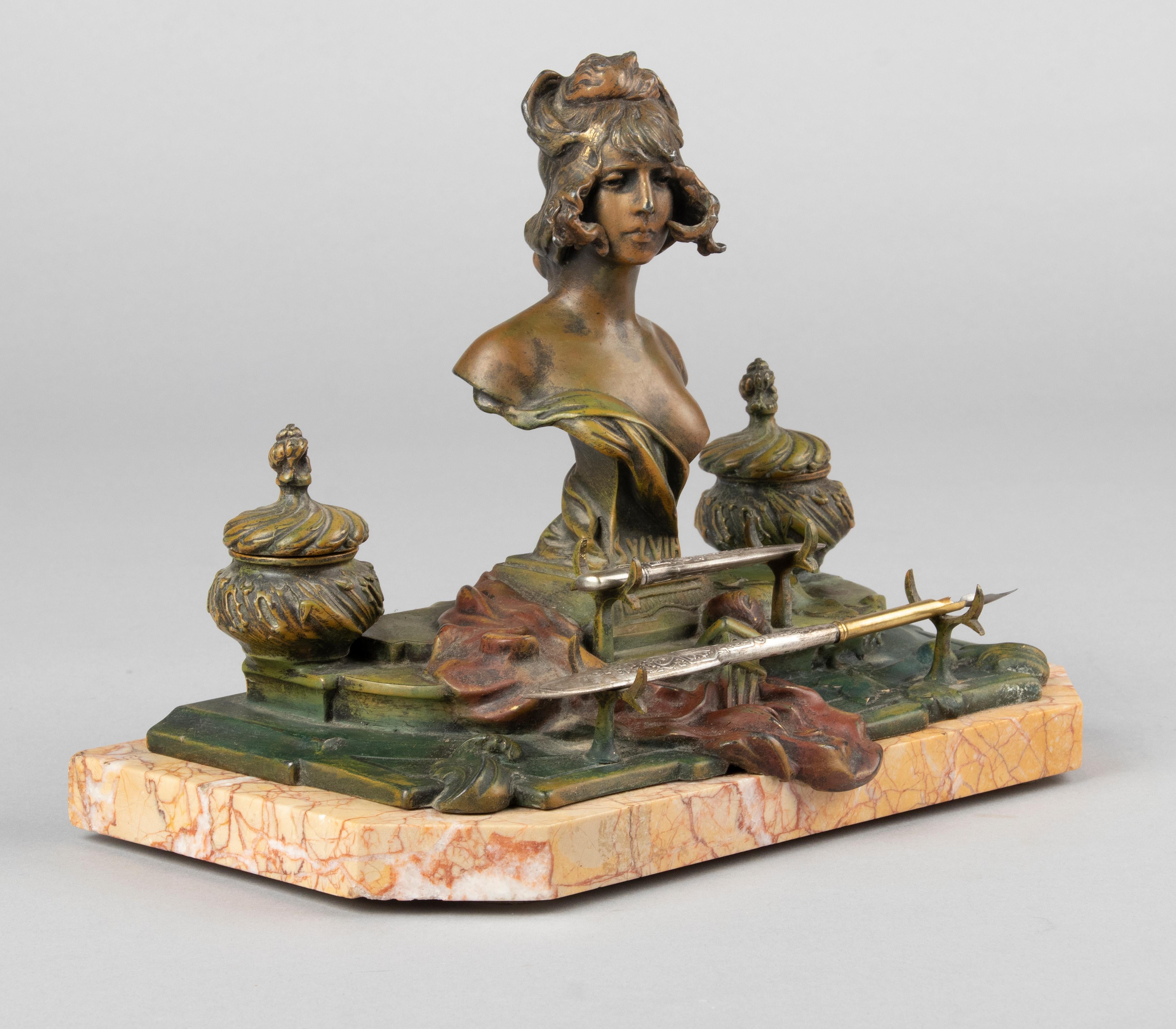 Art Nouveau dektop inkwell. The whole is made of spelter (zinc alloy), with multiple colours patina finish. The inkwell has two wells, containing glass jars. In the middle an sculpture of a woman, signed by A.H. Nelson. Made in France, circa