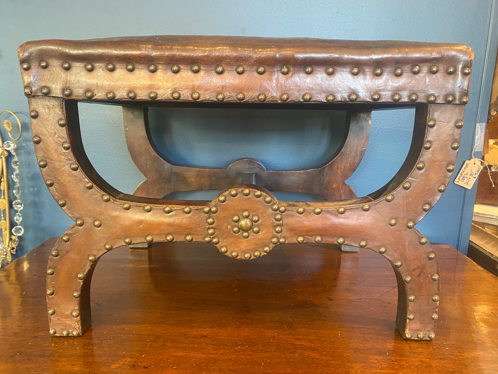 Late 19th century Arts & Crafts brown leather stool with brass nail head trim
Original leather covering is cracked but could be reupholstered or left as is to maintain antique look. Measures: 14.5