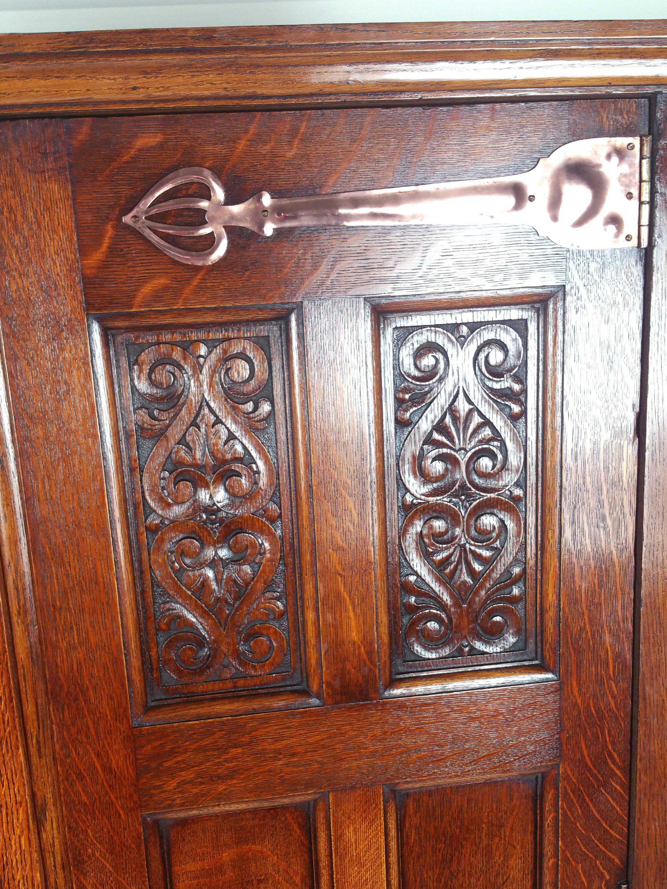 This gorgeous and very useful late 19th century Arts & Crafts two-door hall wardrobe features large ornate copper mounts and carved decoration of the period. The interior is fitted with a stick stand and round mirror. It measures 43 ½ in – 110.5 cm