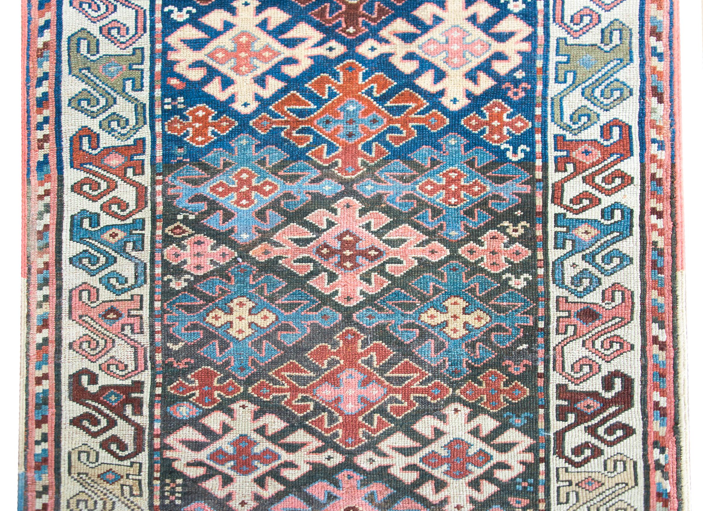 A gorgeous late 19th century Persian Azerbaijani Kazak runner with an all-over stylized floral pattern woven in myriad colors including crimson, cream, pink, indigo, and gold, and all surrounded by a wide border with more stylized floral motifs