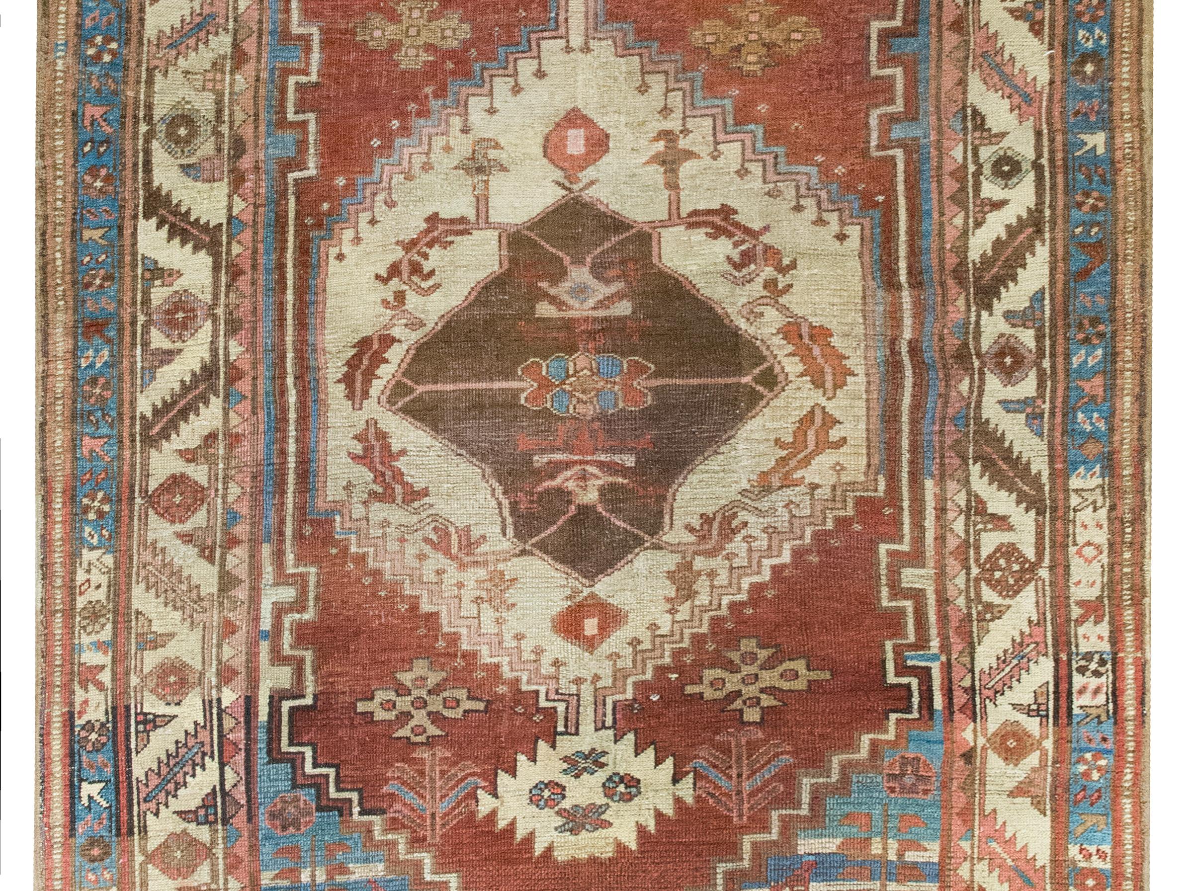 Questo incredibile tappeto persiano Bakshaish della fine del XIX secolo è un capolavoro di tessitura tribale, caratterizzato da un medaglione floreale mozzafiato di grandi dimensioni su un ricco campo rosso mattone ornato da fiori e viti più