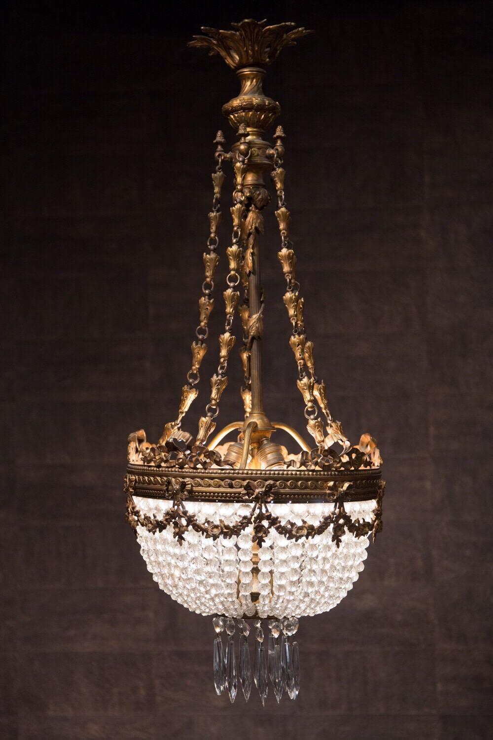Late 19th century French gilt bronze and cut-crystal basket chandelier, hang with many chains of crystal drops, with a central ring terminating in cut-glass font and gilt bronze finial.
This chandelier is a refined and charming statement in