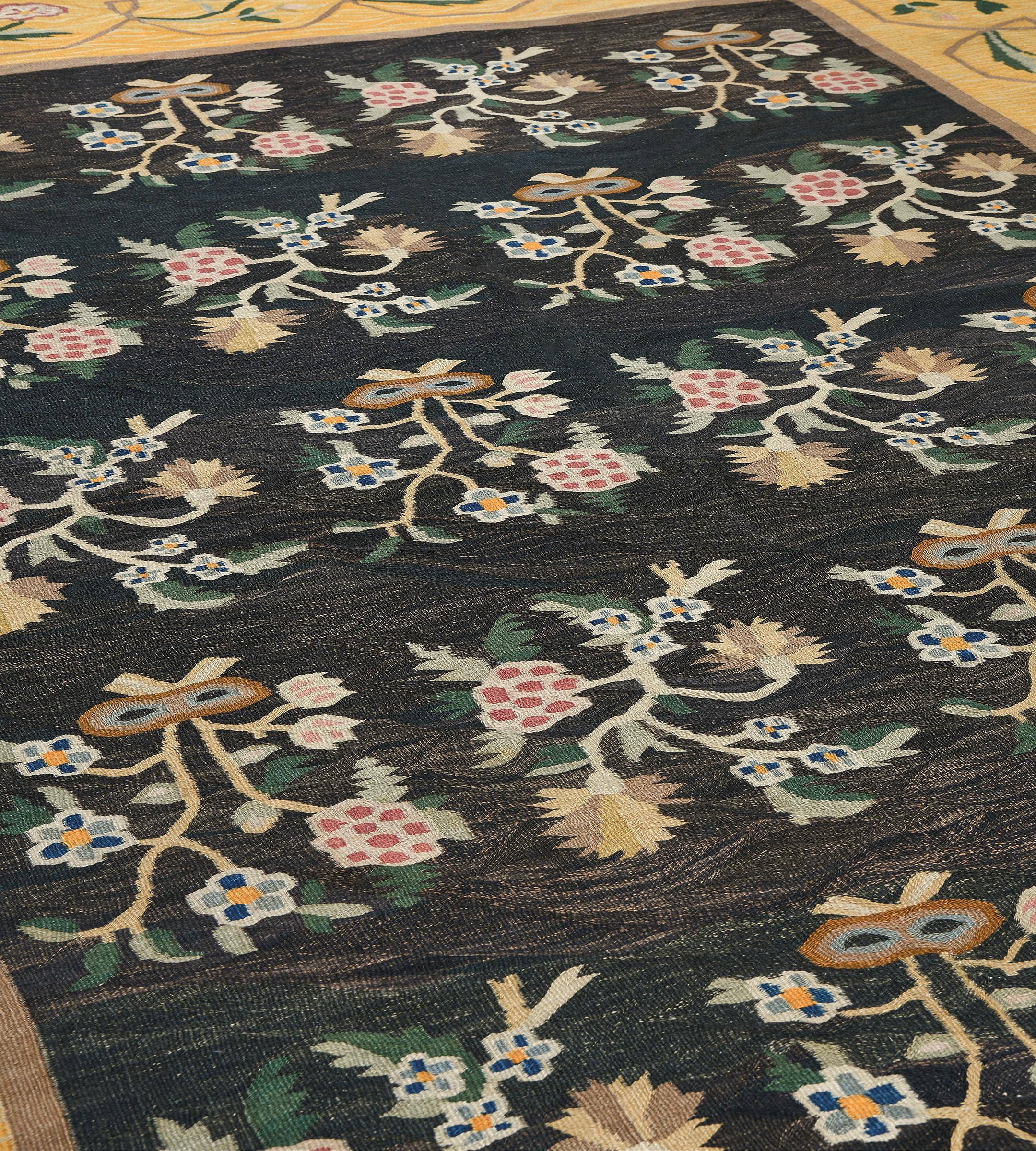 This traditional handwoven Romanian Bessarabian rug has a charcoal-black field with diagonal rows of polychrome floral sprays, in a whimsical golden-yellow border of angular meandering flowering vines.