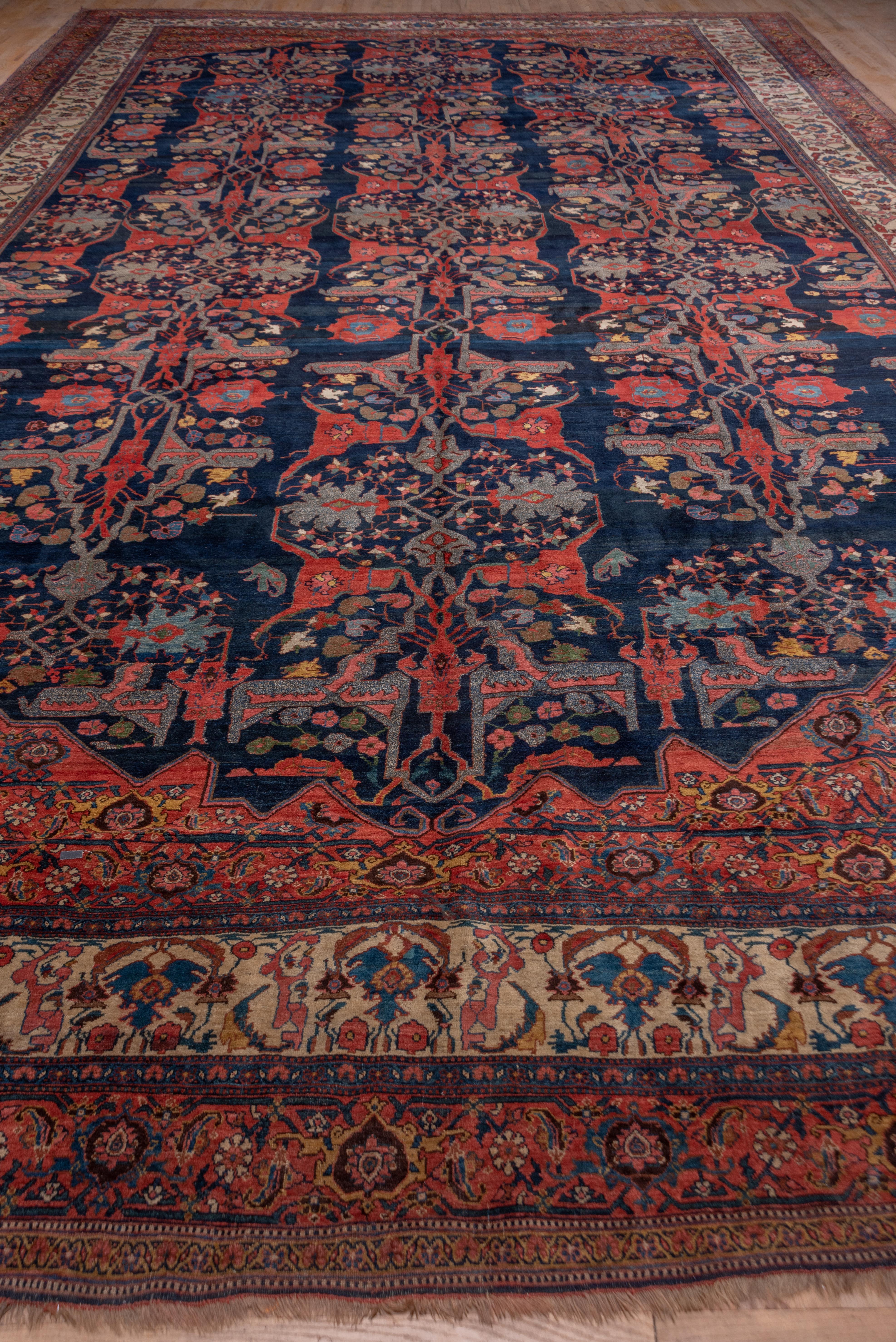 This important Kurdish city carpet displays a Garrus red forked arabesque pattern with palmettes in teal on a navy blue ground. The pattern is organized in three distinct columns rather than strictly all-over. The red corners present repeated turtle