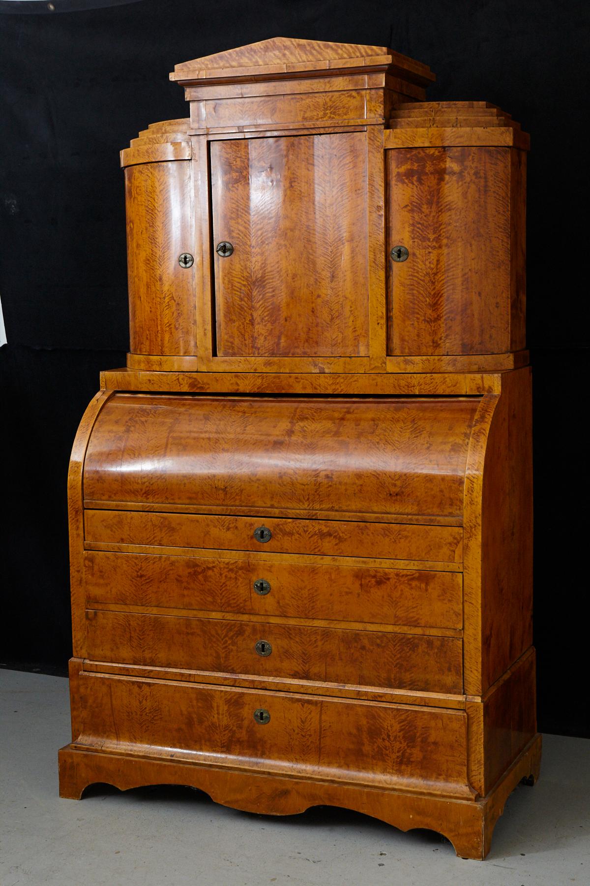 Fine walnut veneer Biedermeier cylinder secretaire/bureau, circa 1870. Typical construction with three sections. The top section has a superstructure with a central door flanked by two concaved side doors. All doors reveal interior shelving.
The