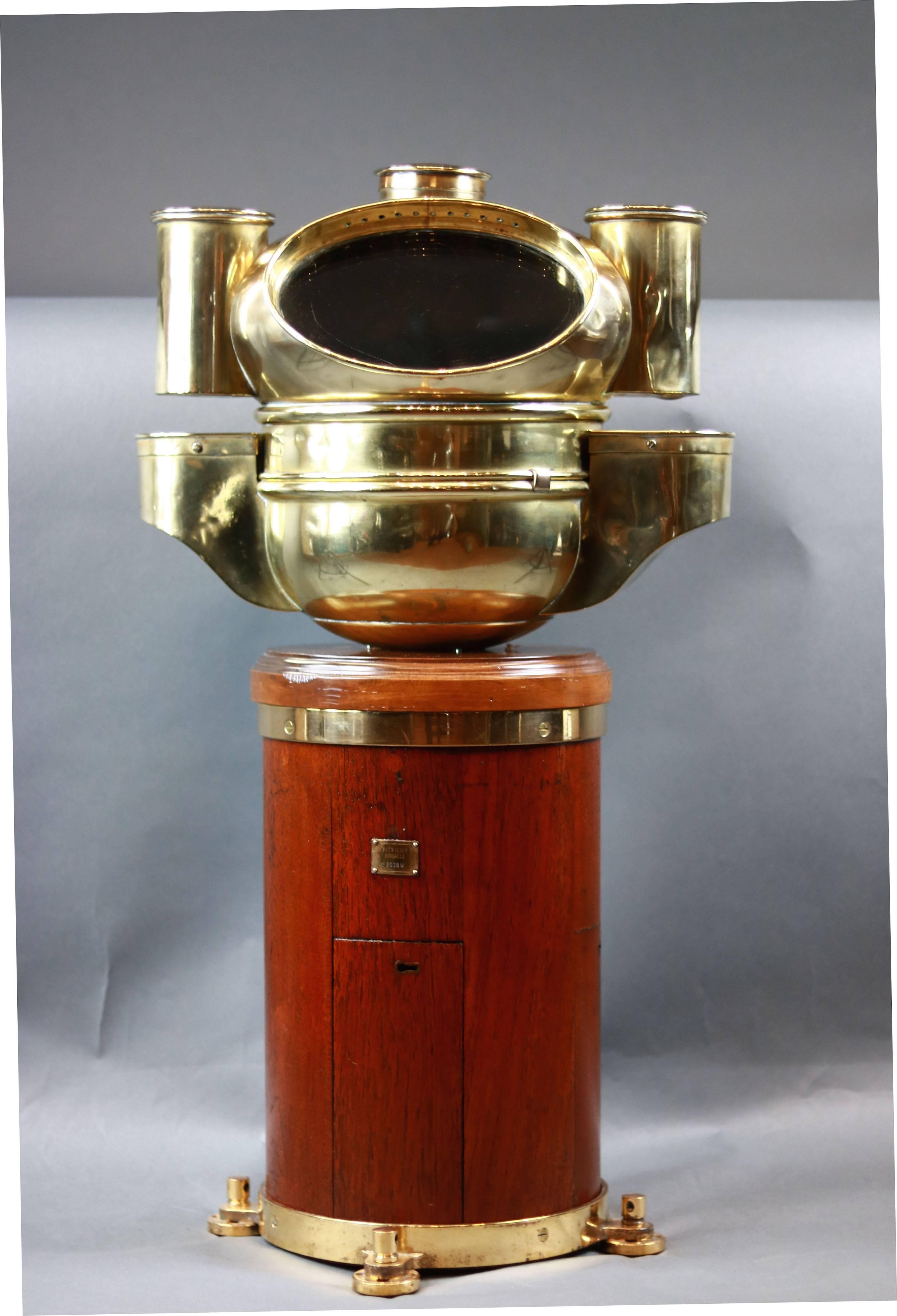 English yacht binnacle by Pascall Atkey of Cowes. Round, varnished mahogany base with brass feet. Hood is solid brass with side burner housing. Compass inside reads 