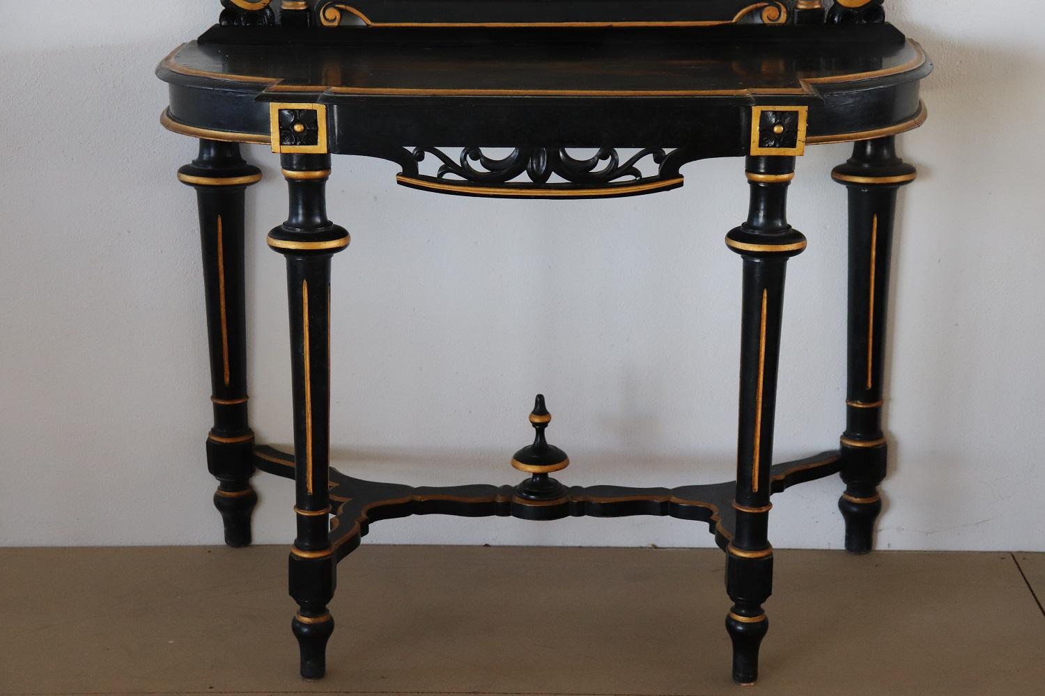 Antique Italian console table 1880. The console is made of solid carved walnut with many curls and swirls of decoration. The walnut wood is colored black with refined golden frames that enrich this splendid console. Perfect to be placed even in