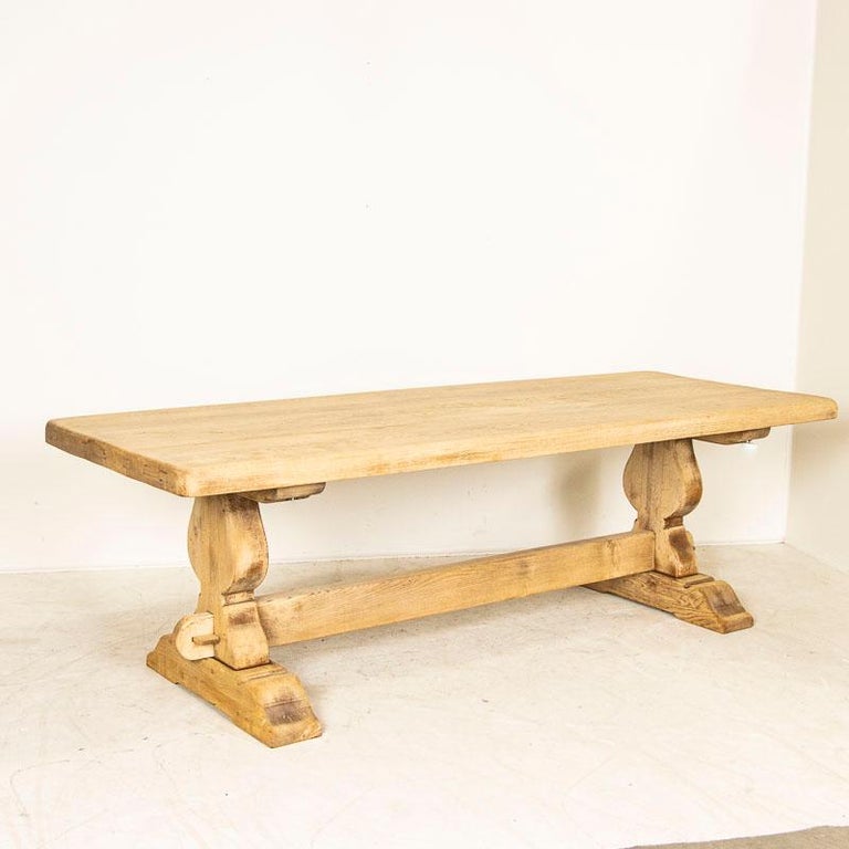 Large and impressive, this French country farm table has been given new life with a bleached oak finish, adding a fresh look to this timeless classic. Note the thickness of the solid oak top and heavy trestle base. This large dining table has been