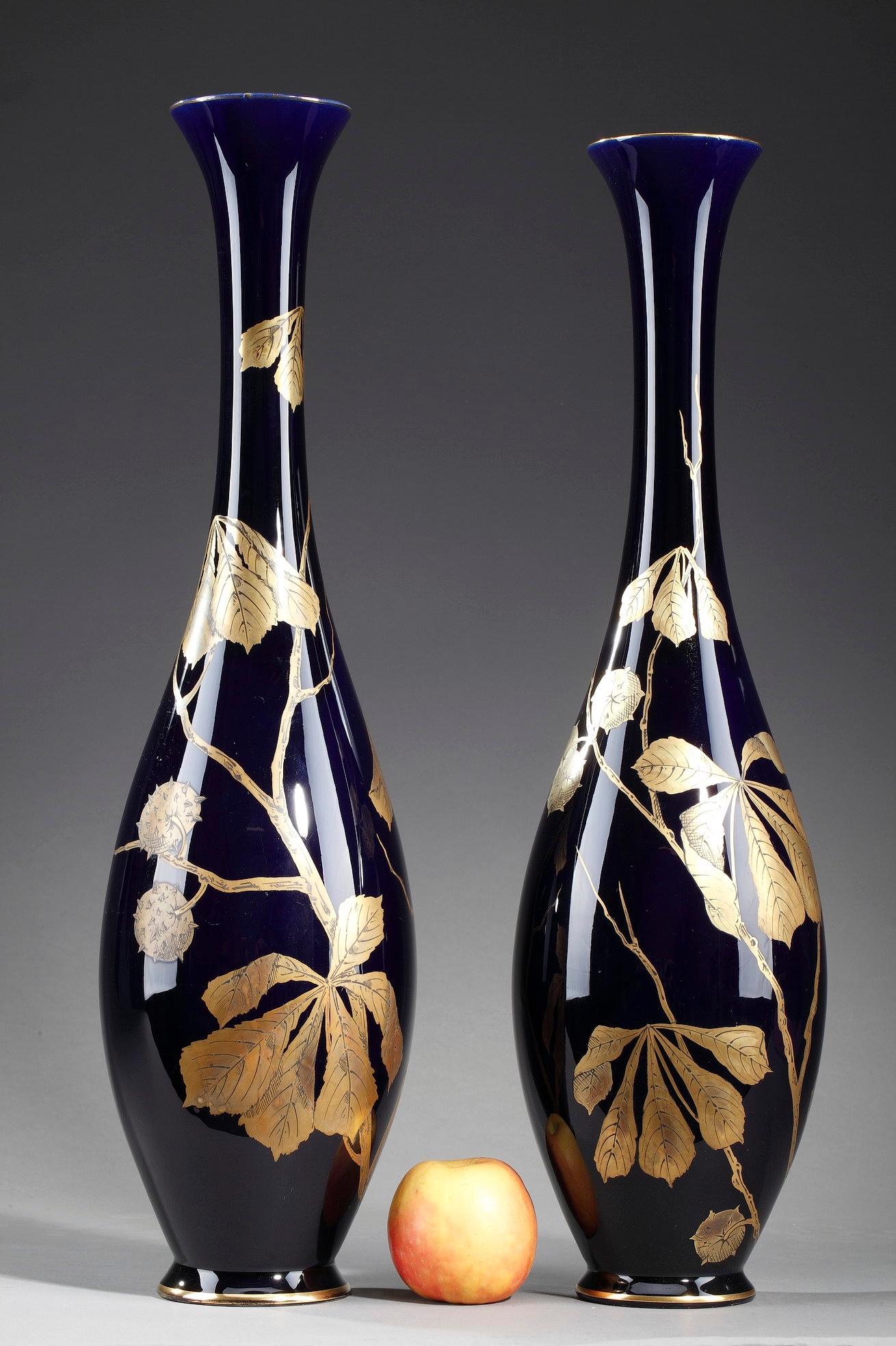 Two porcelain vases intricately decorated with chestnut branches and chestnuts in their bugle in gold on bleu de Tours background. The motif covering the neck and the belly of each vase, is typical of the Art Nouveau decorations of the French