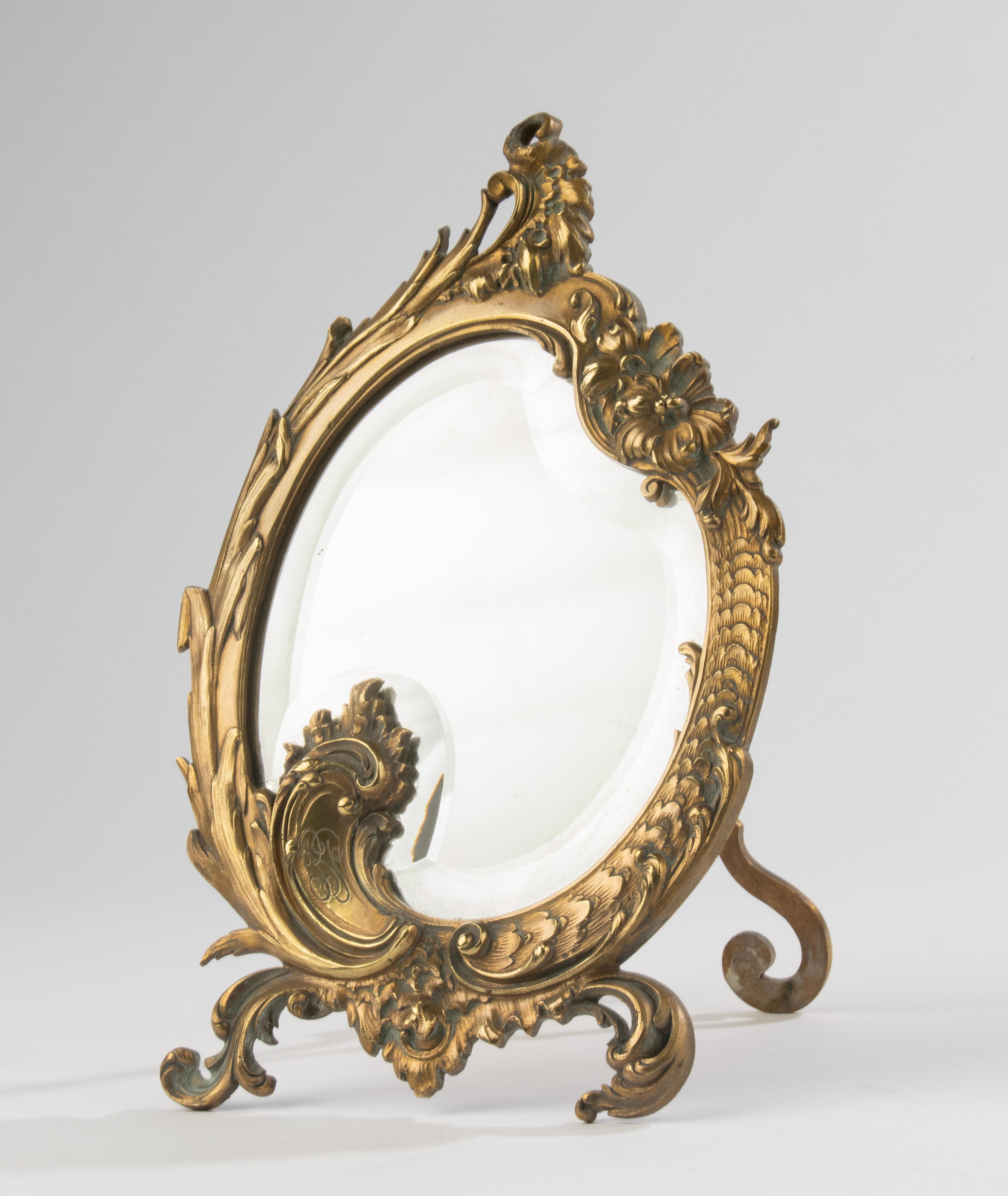 Un beau miroir de table ancien, en bronze finement coulé. Belle patine dorée et  décorée dans le style rococo. Monogramme avec les lettres B.P. 
Le verre du miroir a un bord à facettes. Le miroir de table est en très bon état. 

Dimensions : 21,5 x