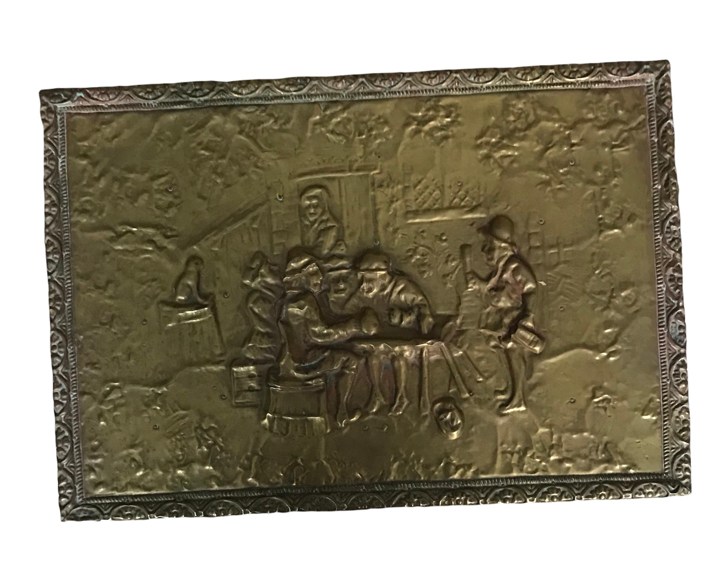 Impressive Late 19th Century firewood box with embossed brass tin outside. The scene depicts people at a table outside a house. The box has its original caster wheels and the lid has attached chain. Originally purpose was as a decorative piece to