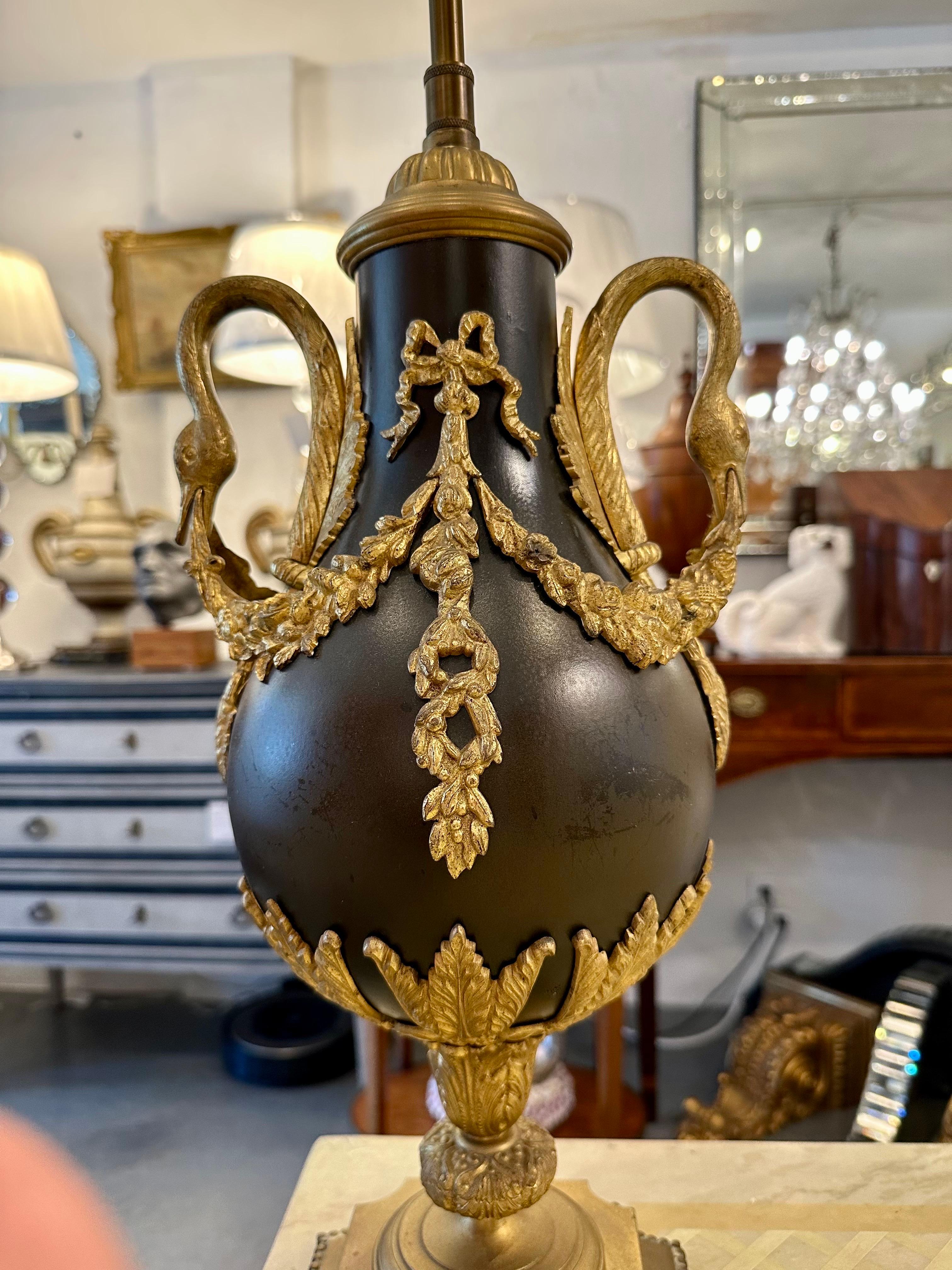 Il s'agit d'une imposante urne en bronze de la fin du XIXe siècle, décorée d'anses de cygne et de guirlandes en bronze doré, ultérieurement électrifiée.