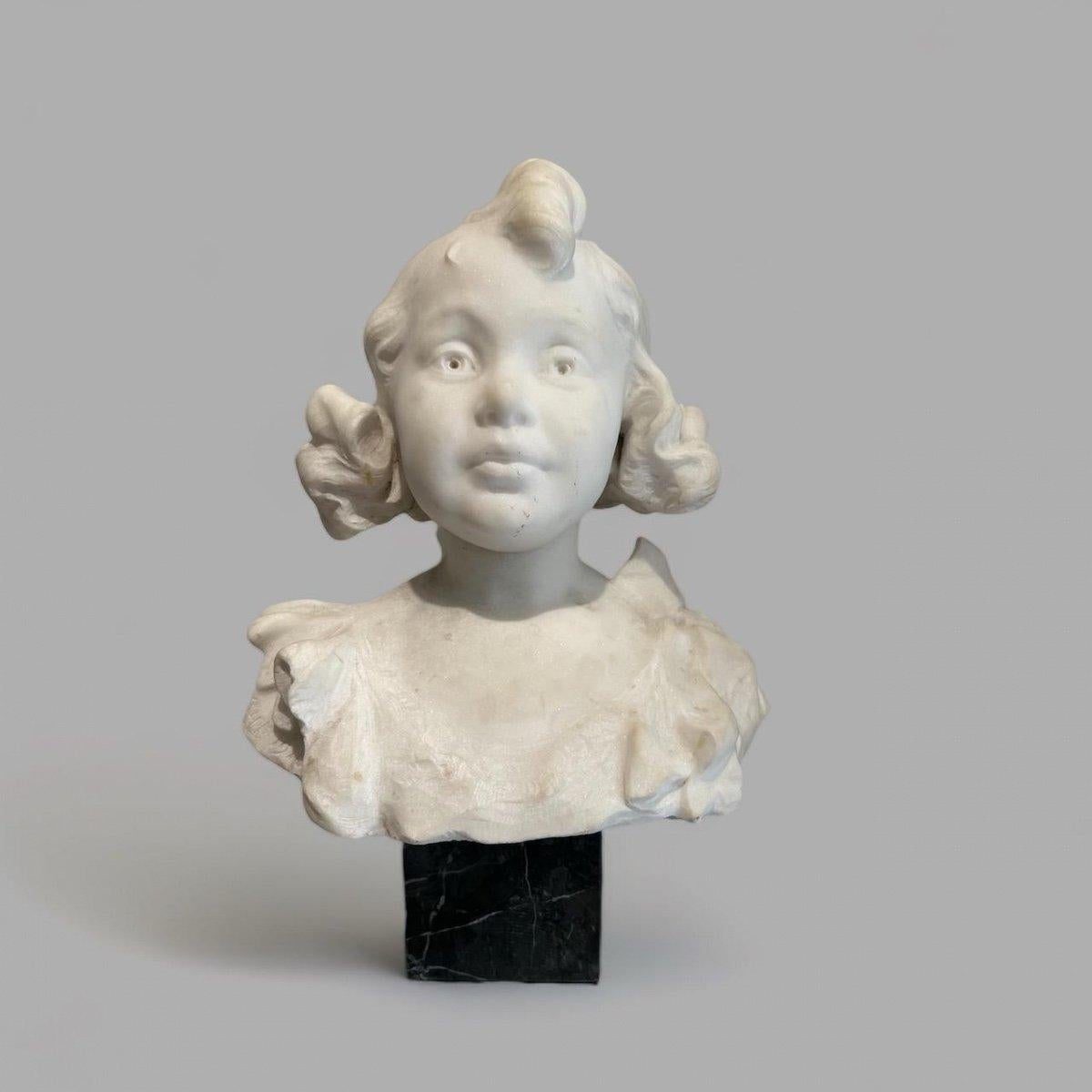 This bust of a young girl in Carrara marble from the late 19th century beautifully captures the innocence and charm expressed on the subject's face. The sculpture exudes remarkable expressiveness which is particularly evident in the delicately
