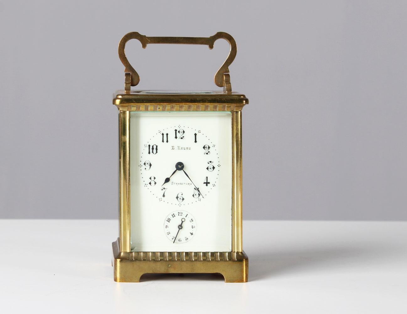 Antique travel clock with alarm function. 
H x W x D: approx 12 x 8 x 6 cm.

Brass case glazed on all sides. Dial with signature: E. Keltz Strasbourg.

Eight-day movement. With old key. 

Running condition. Brass with authentic patina. Easy
